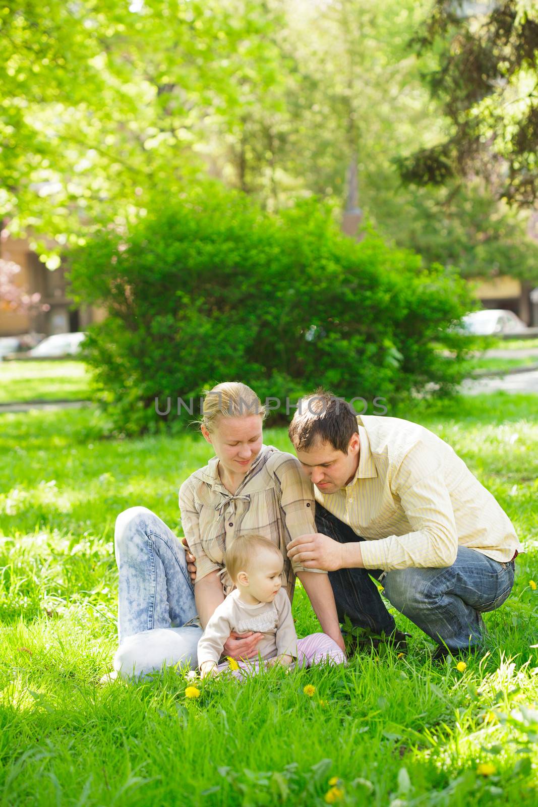 Family with child play in the park on green grass