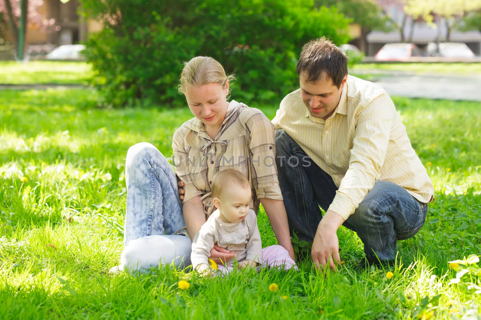 Family with child play in the park on green grass