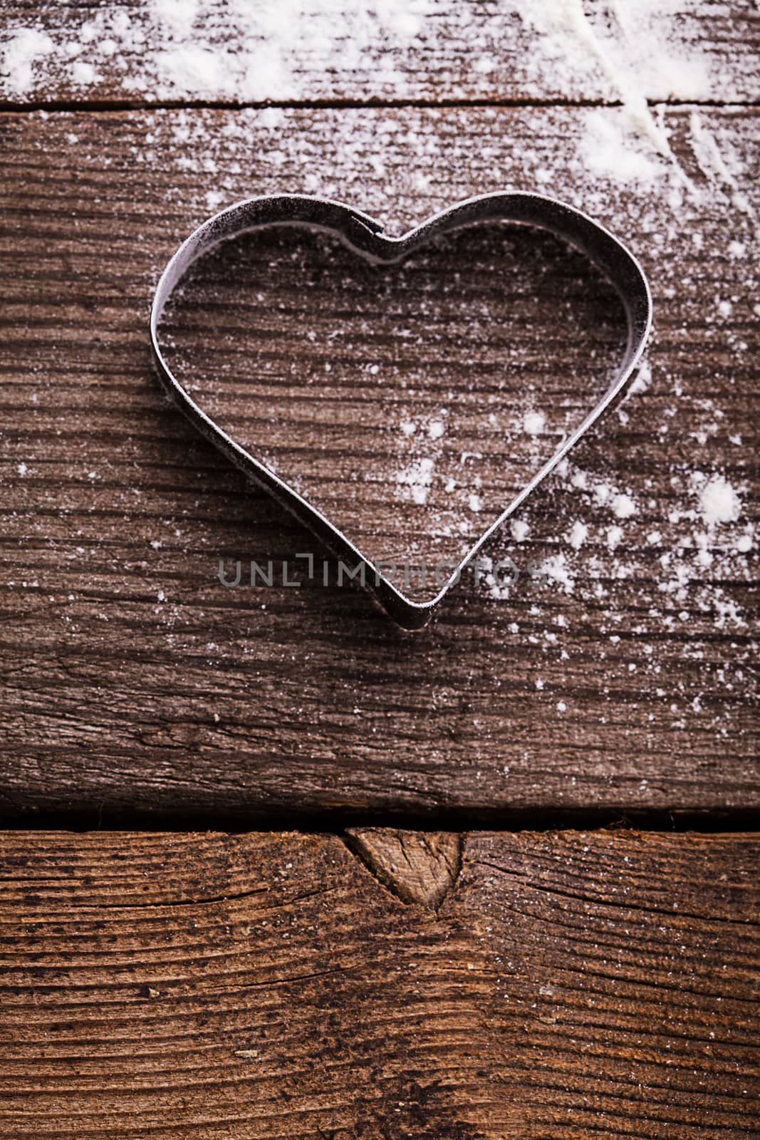 Cookie cutter heart shape on the kitchen table and flour