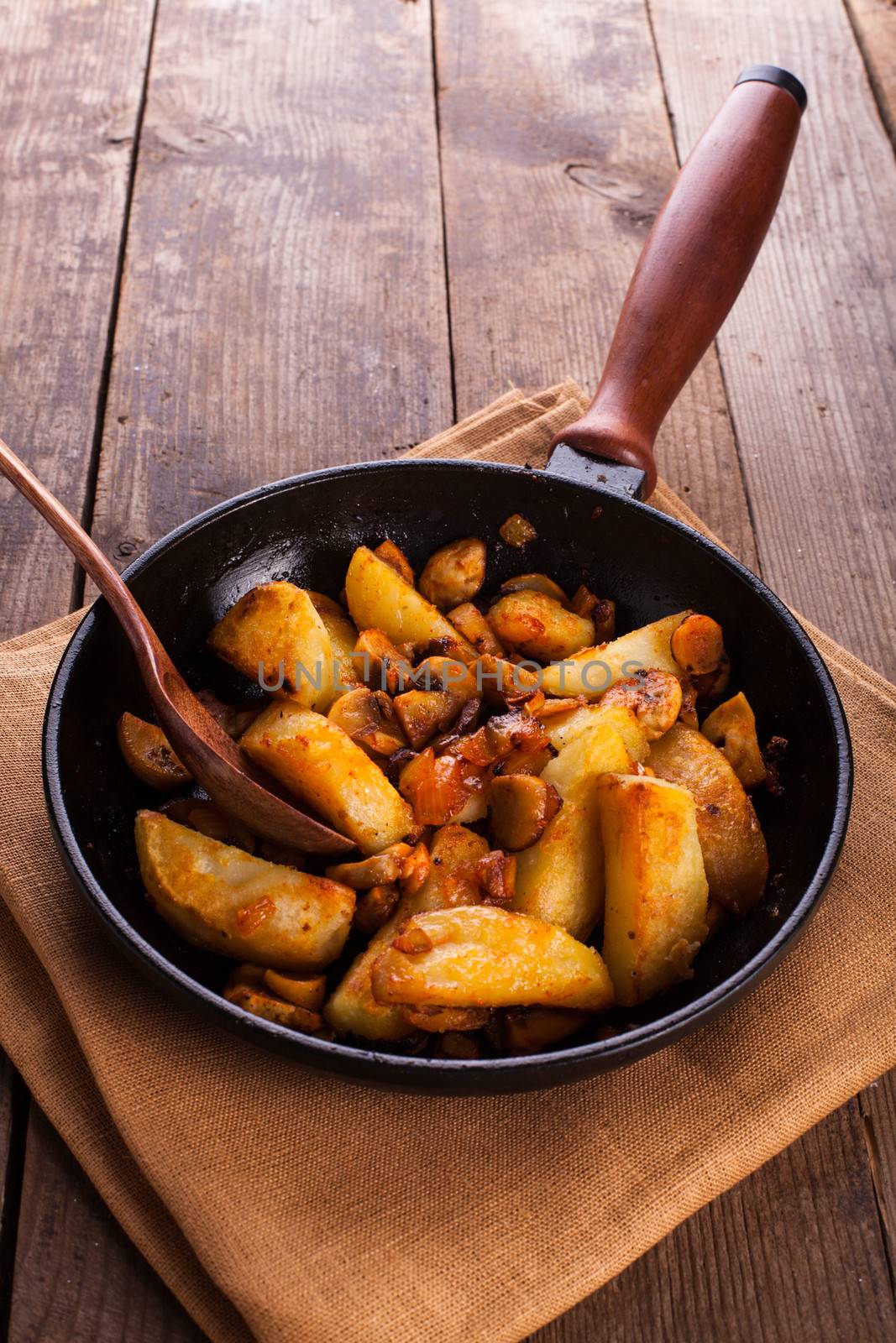 Fried potato and champignons in the cast-iron frying pan