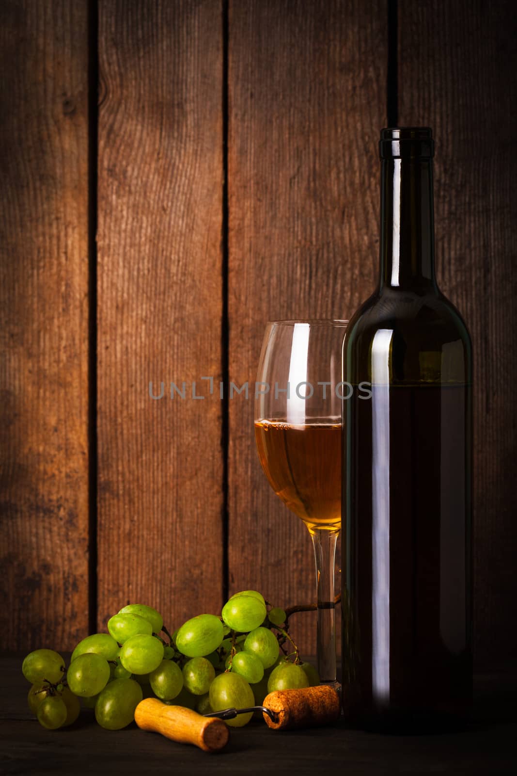 White wine, grapes, corkscrew, and bottle on wood background closeup