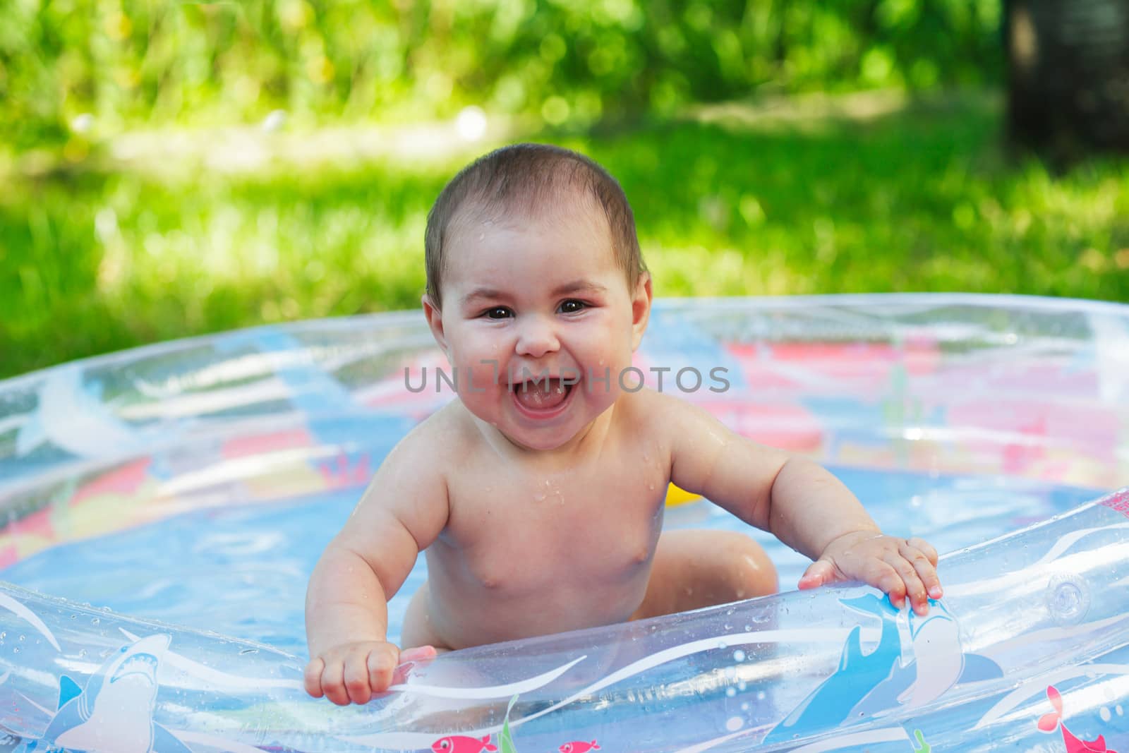 Cute baby in the inflatable pool on grass