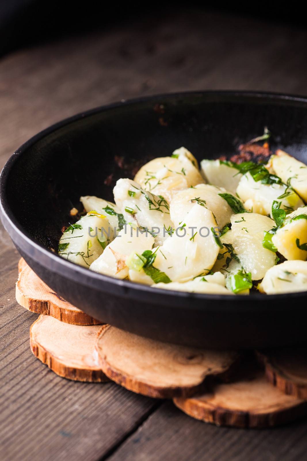 Rustic baked potato with herbs in frying pan
