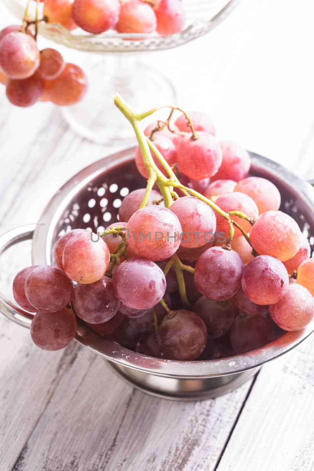 Big red grapes in  colander on the wood background