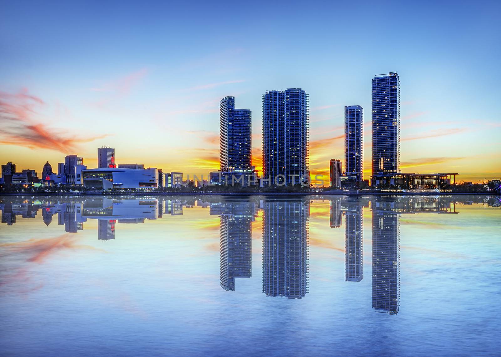 Miami city skyline panorama at dusk with urban skyscrapers over sea with reflection 