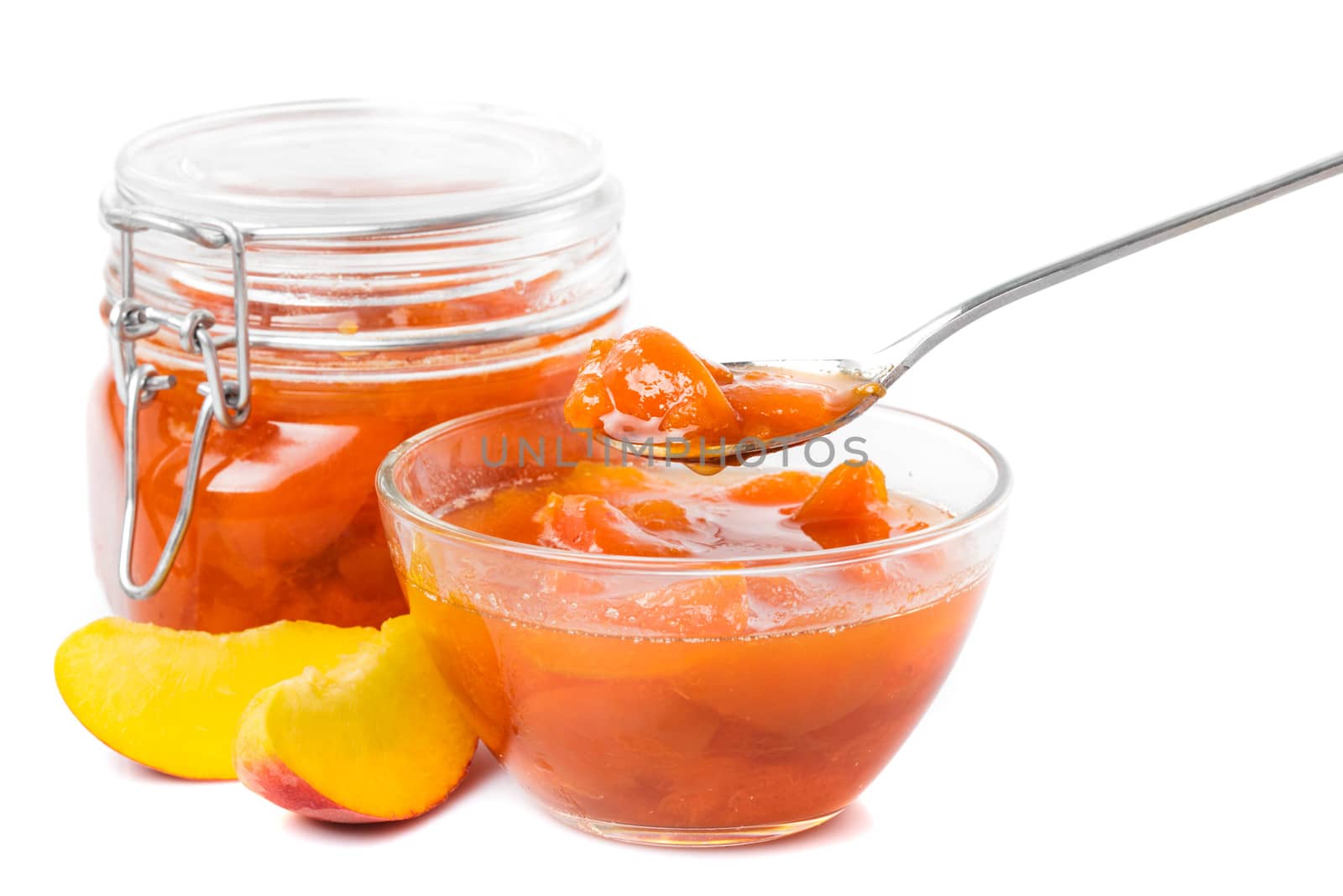 Tasty peach jam in glass jar with fruits over white