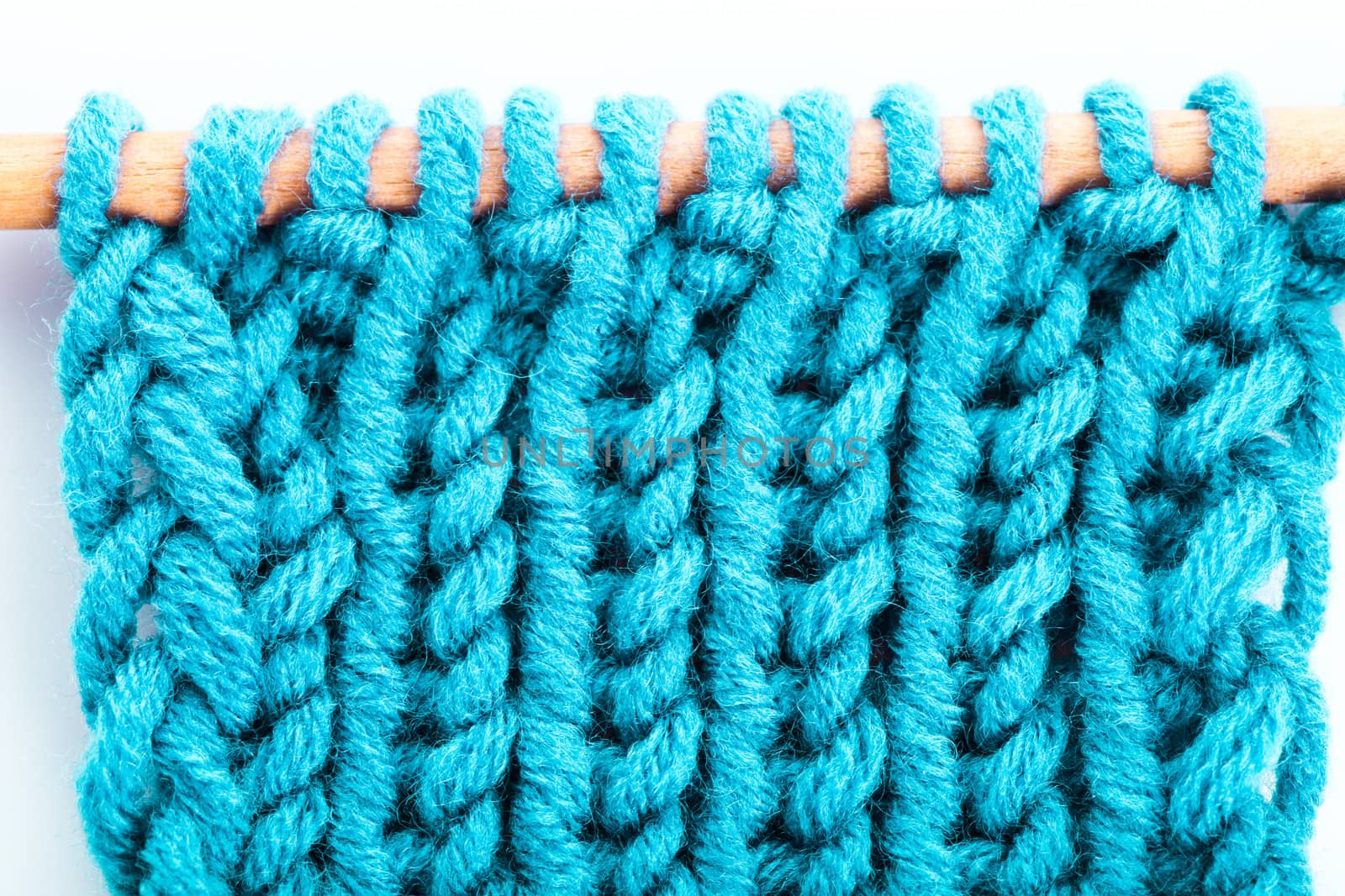 Turquoise knitted background closeup on the needle, the front