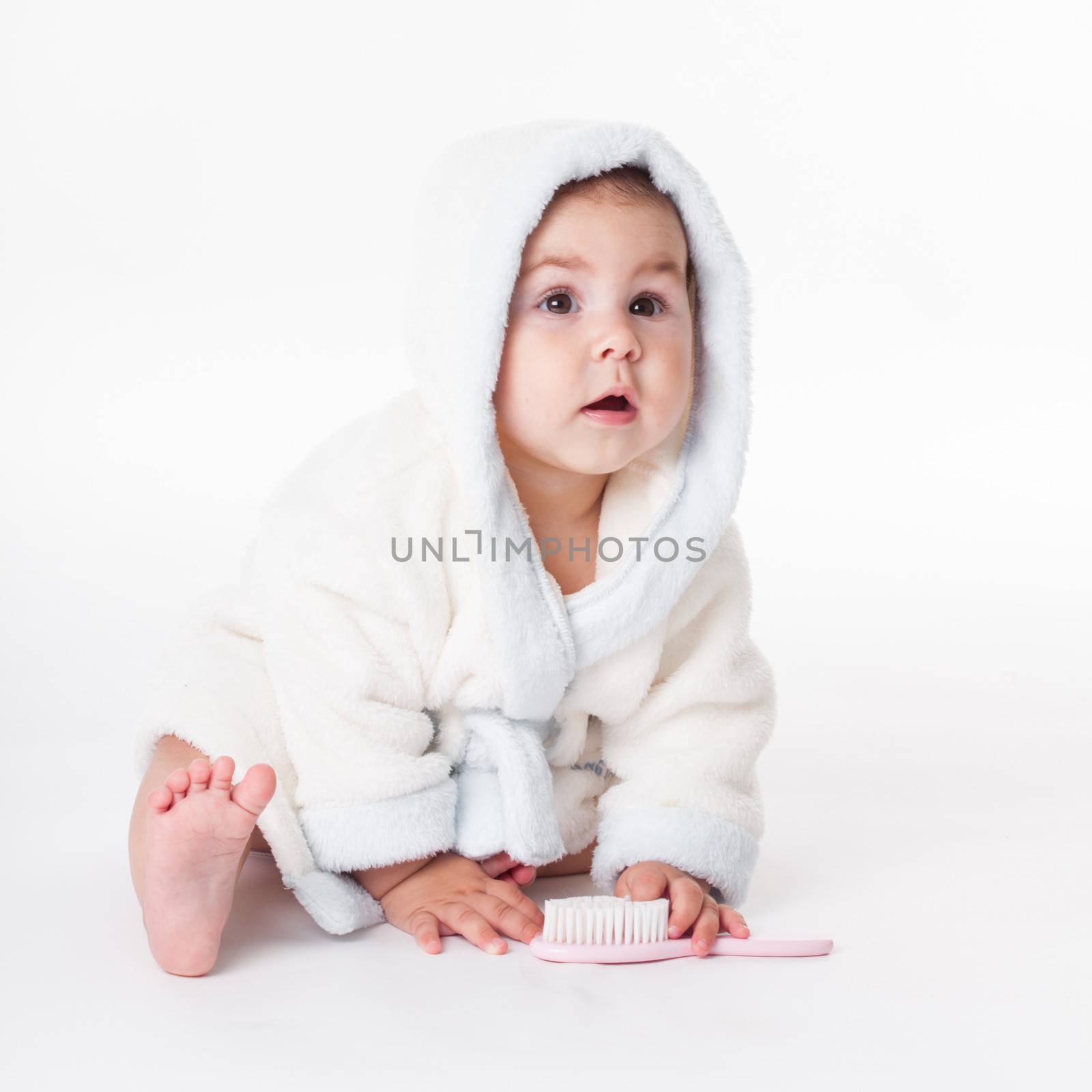 Baby in a bathrobe after bath with comb