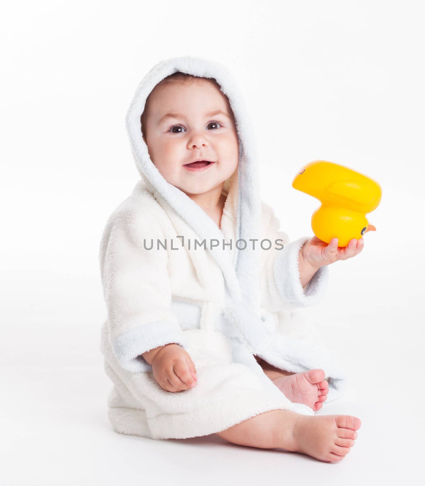 Baby in a bathrobe after a bath with yellow toy isolated