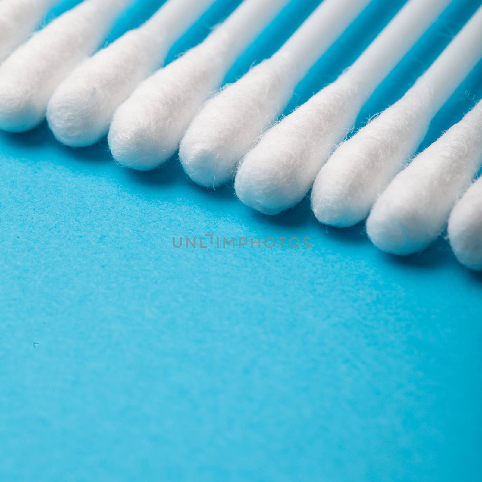 White cotton ear sticks on blue background macro