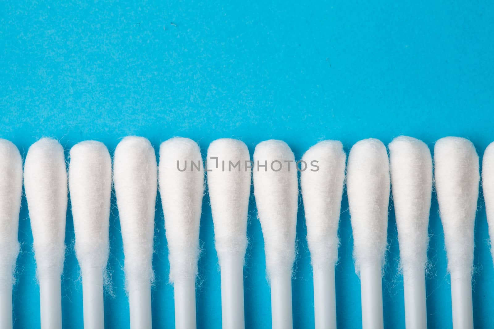 White cotton ear sticks on blue background macro