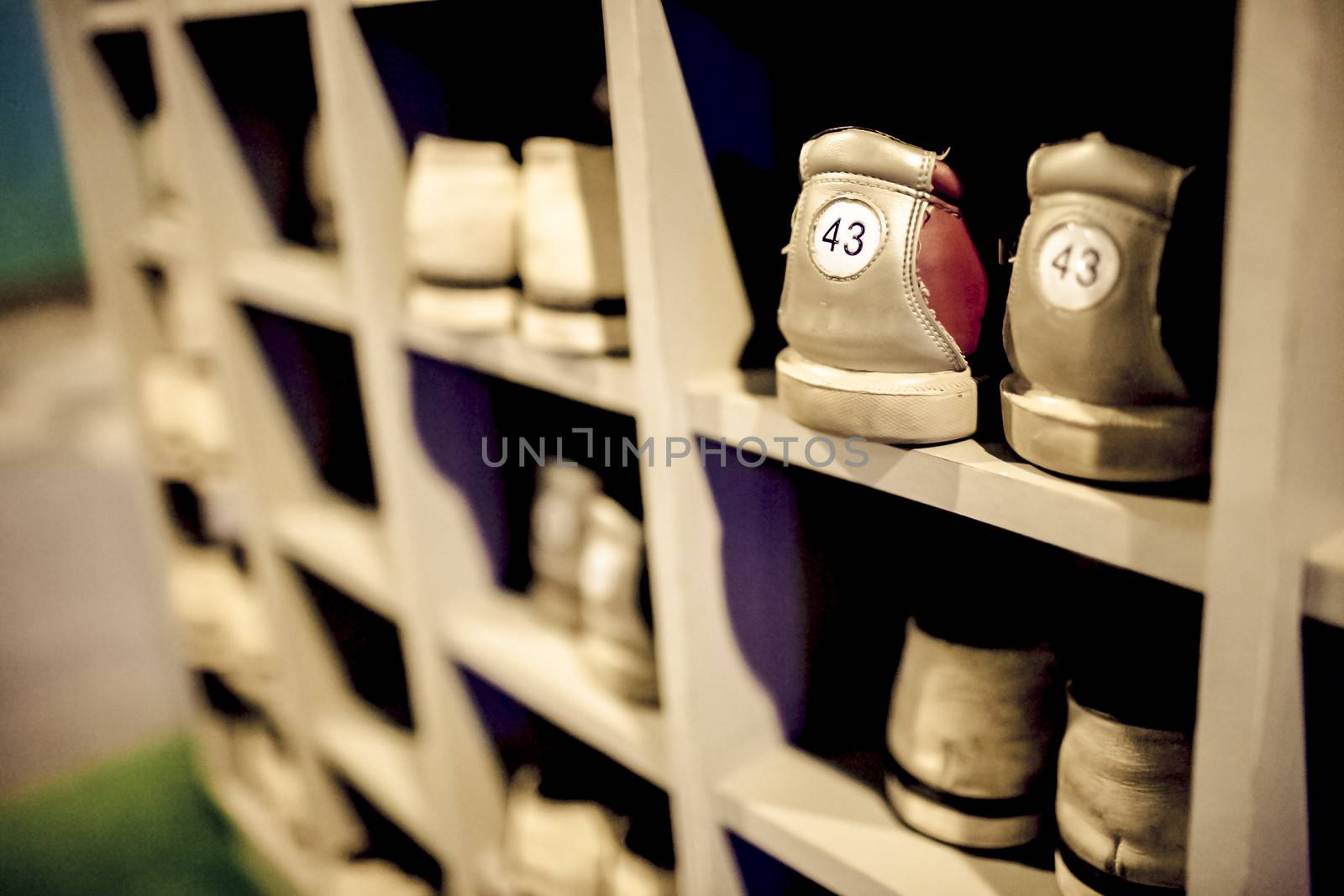 Shoe cupboard by the bowling alley, old  bowling shoes put in order, visible shoe sizes, numerous pairs of shoes, shallow DOF.