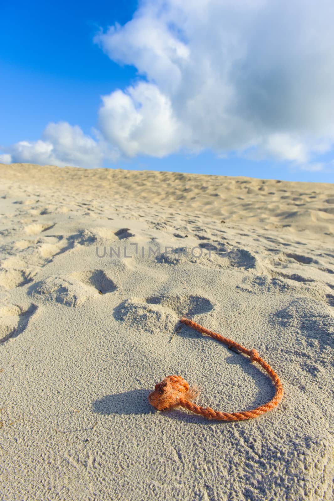 A fragment of the net rope on the beach, sky and white and grey clouds in the background.