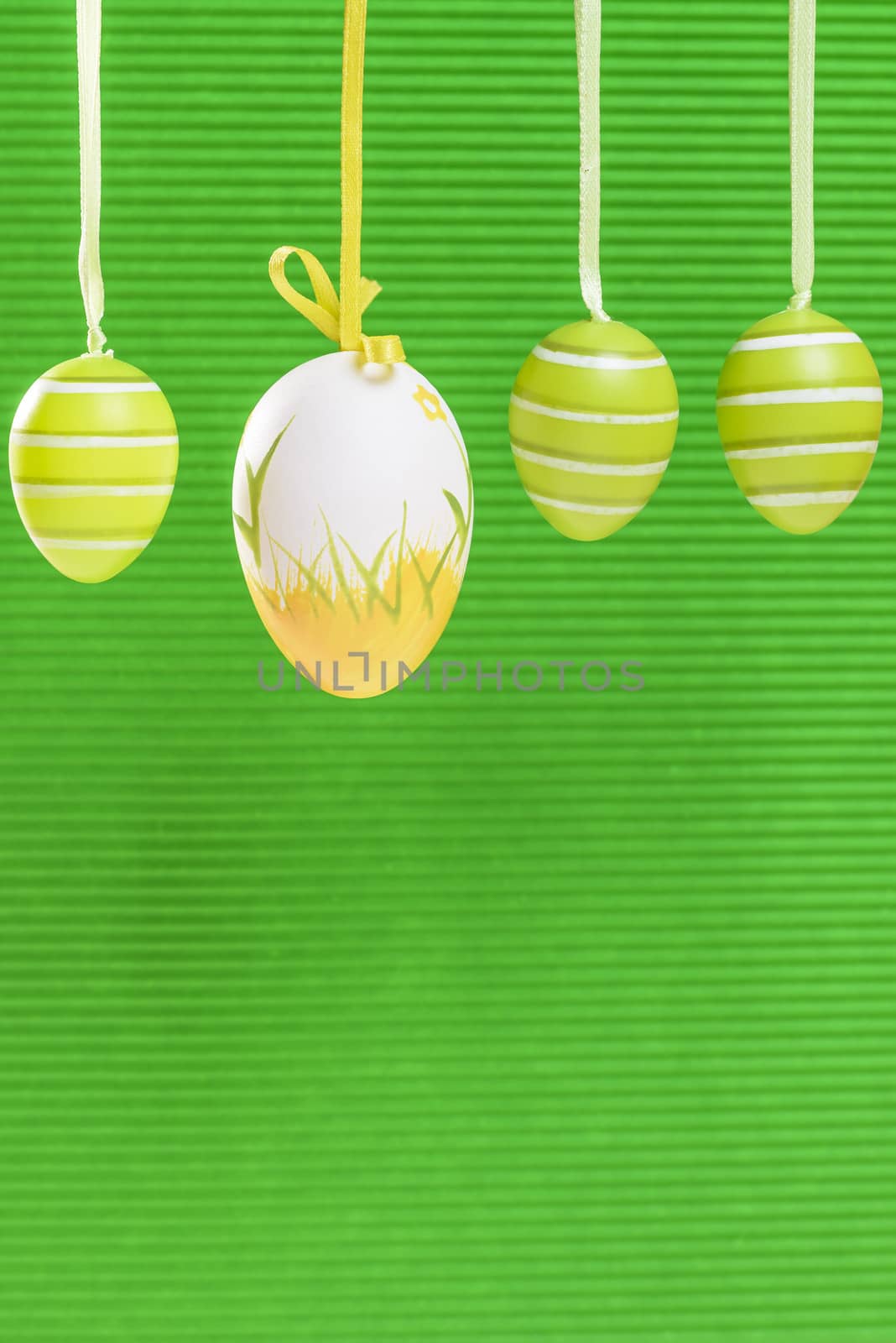 Easter decorated eggs on green backround, eggs in white and green and yellow colours, space for text, vertical frame.