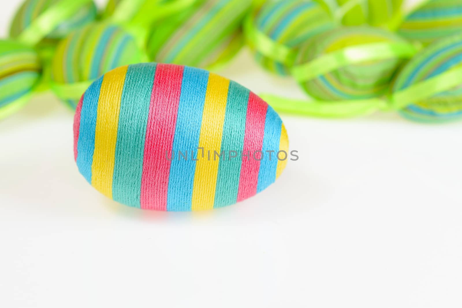 Photo presents Easter decorated striped eggs scatterded on white background.