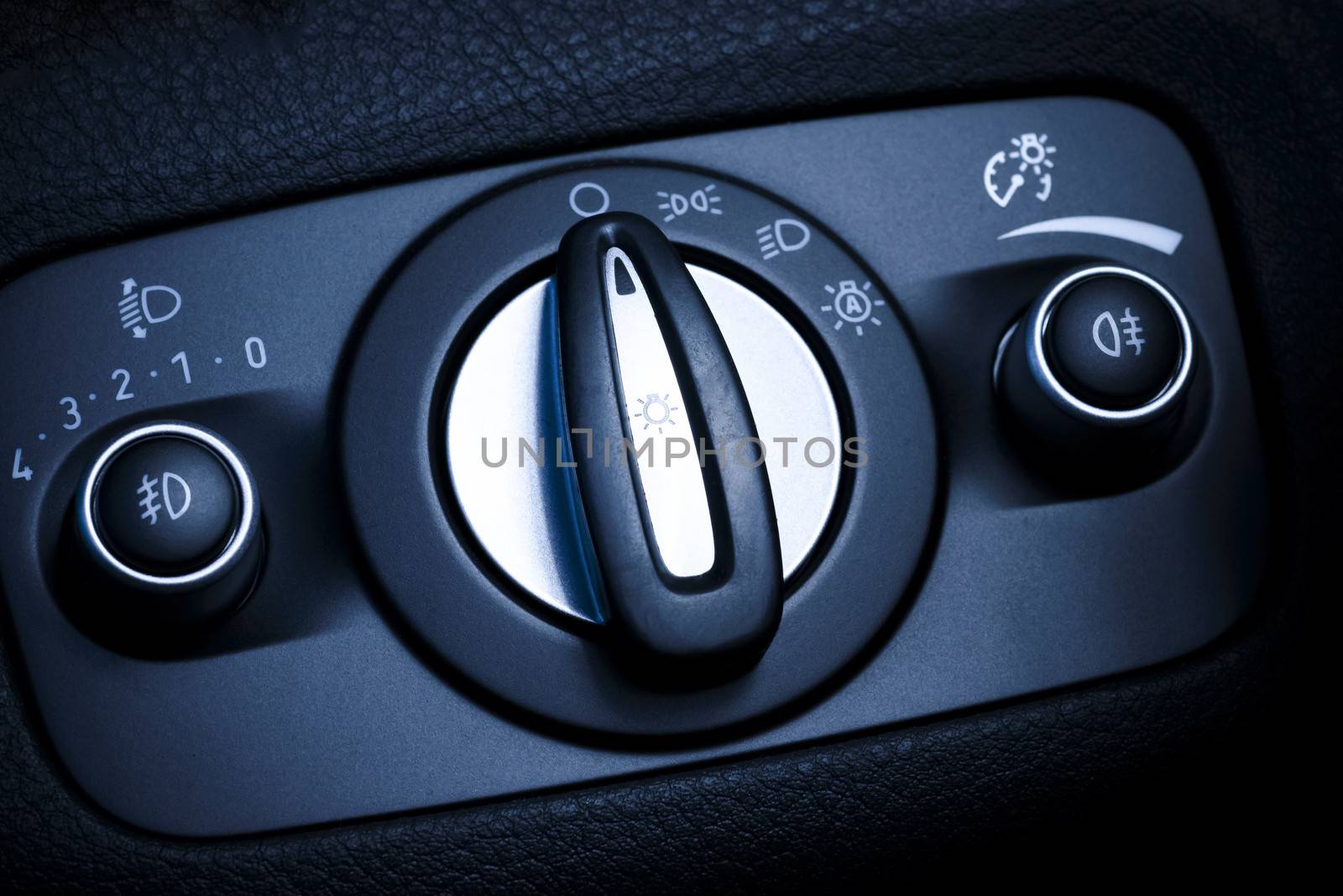 Photo presents interior of car/vehicle, visible headlights switch with regulation and illumination of central panel adjustment.