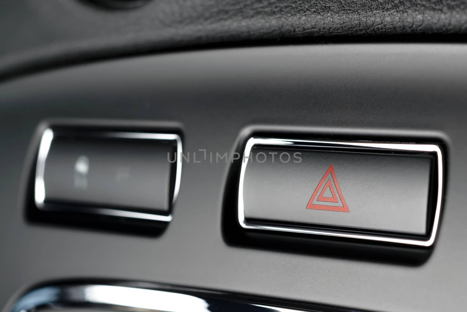 Button of vehicle, car hazard warning flashers button with visible red triangle, visible  fragment of control panel, visible red triangle emergency symbol.