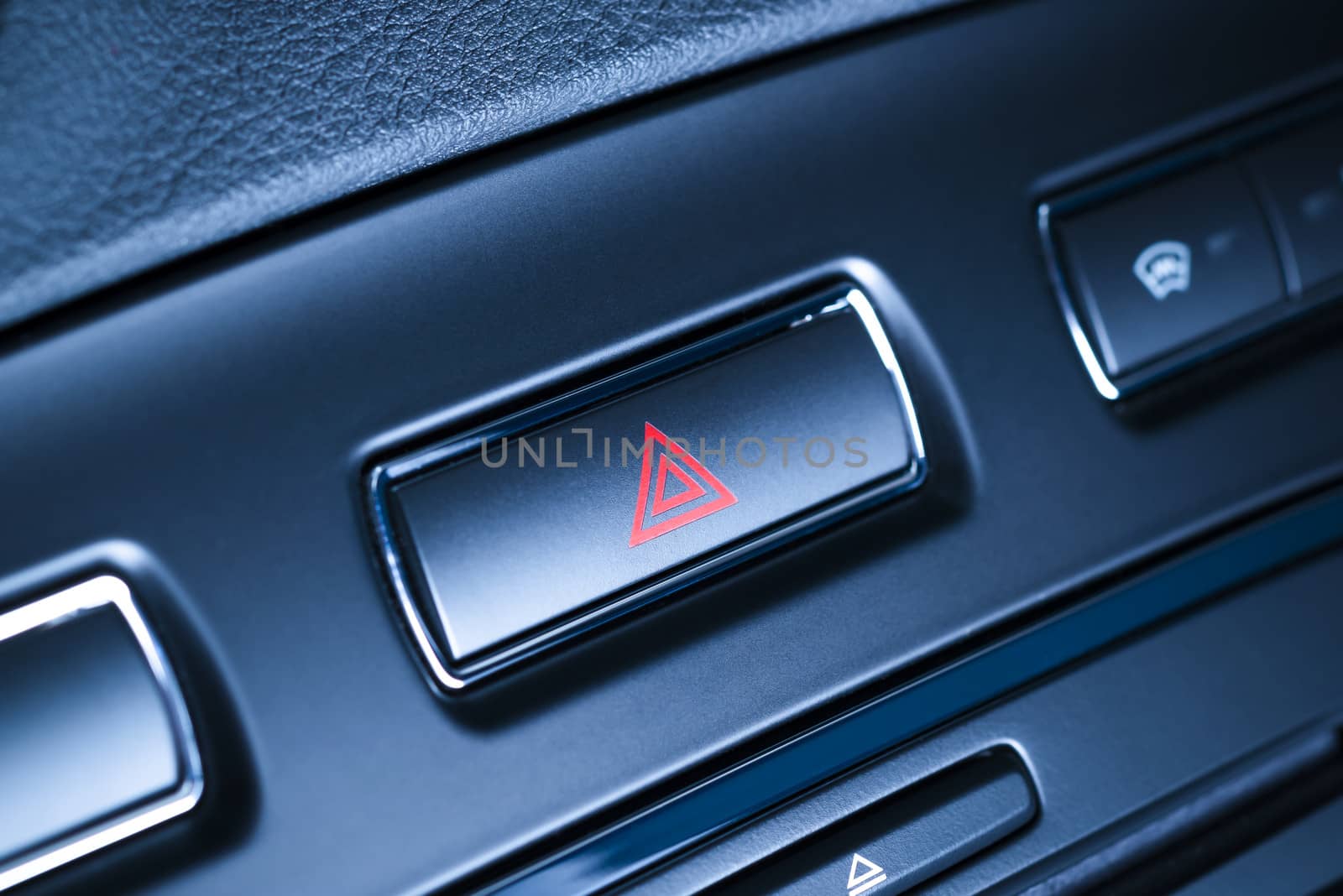 Button of vehicle, car hazard warning flashers button with visible red triangle, visible  fragment of control panel, visible red triangle emergency symbol.