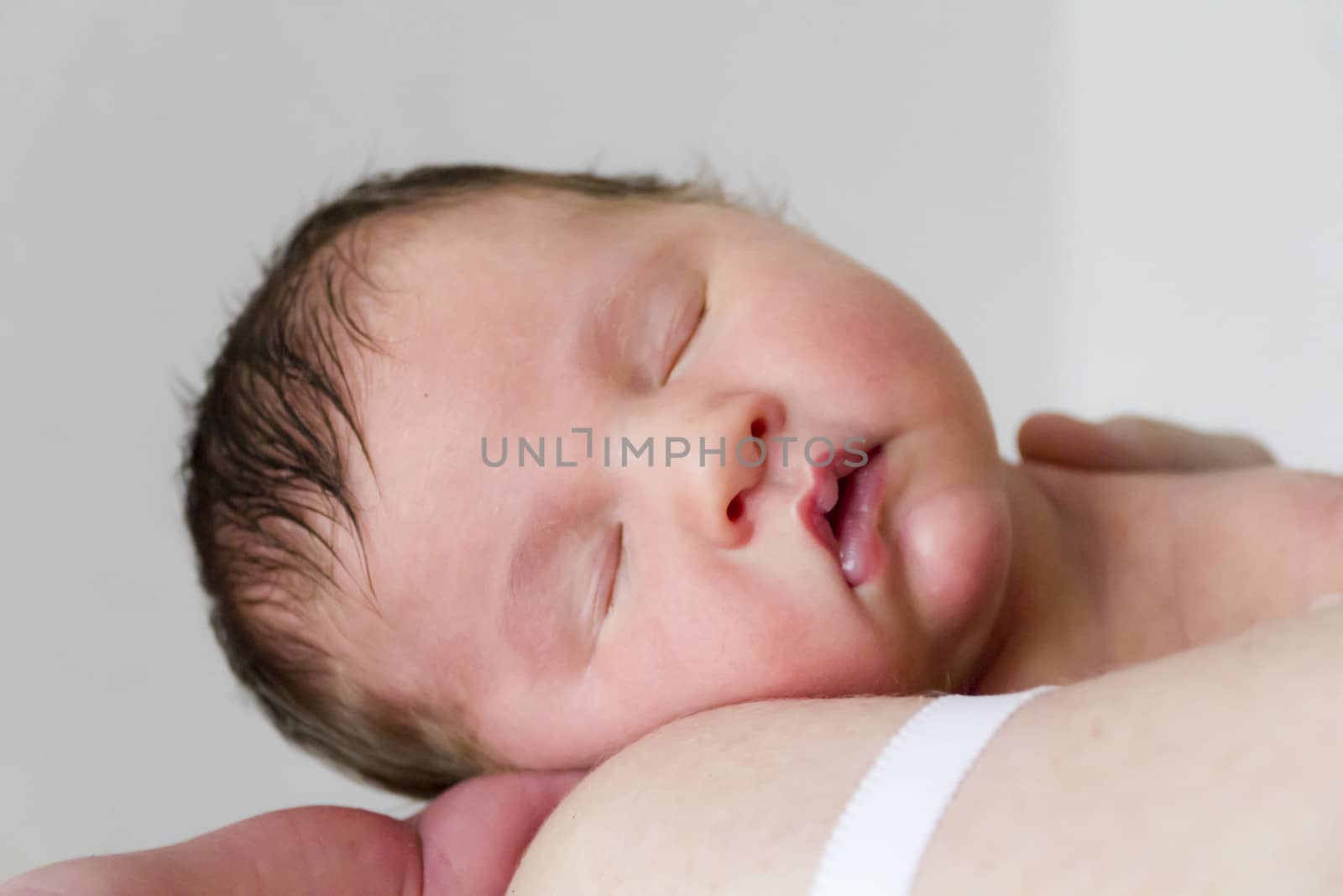 Cute infant sleeping on the mother’s shoulder