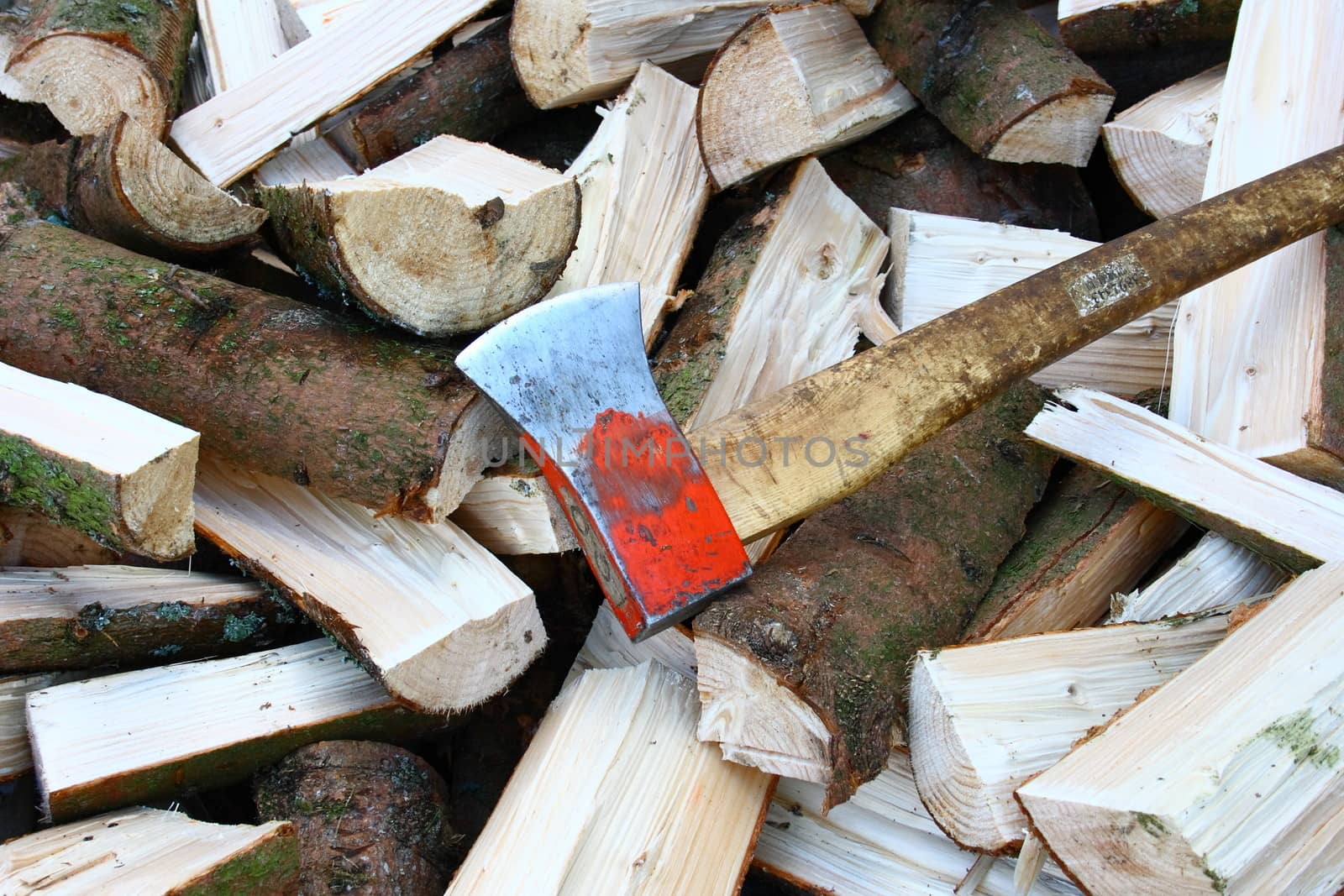 A pile of split firewood logs with an ax