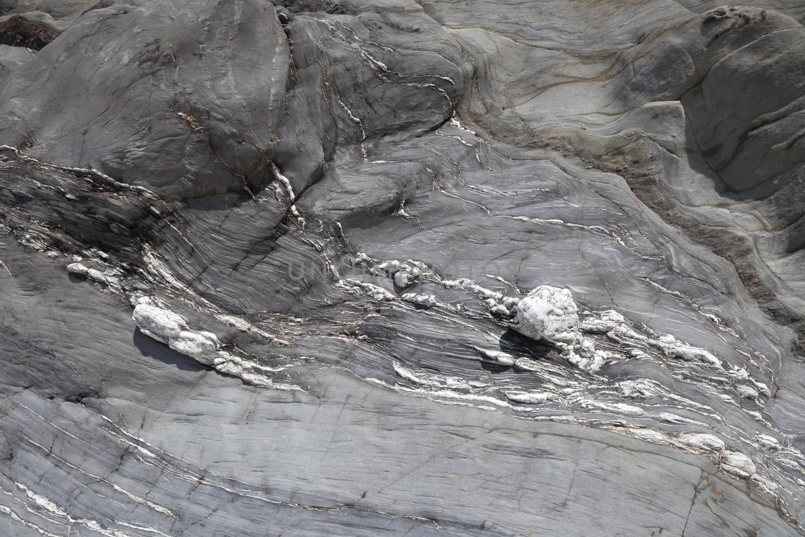 Grey coastal rock formation with marbling, Lantic Bay, Cornwall, England.