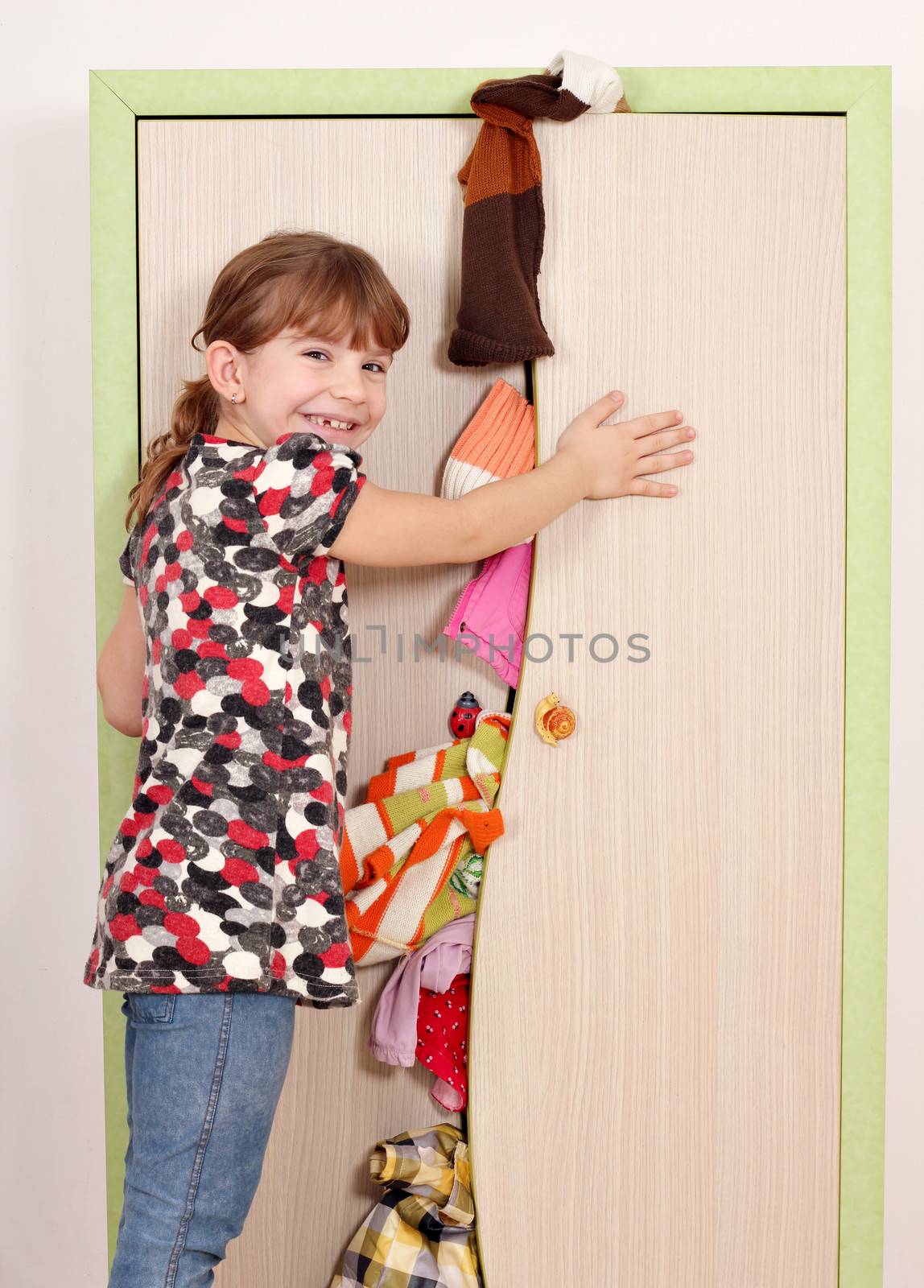 little girl trying to close messy closet  by goce