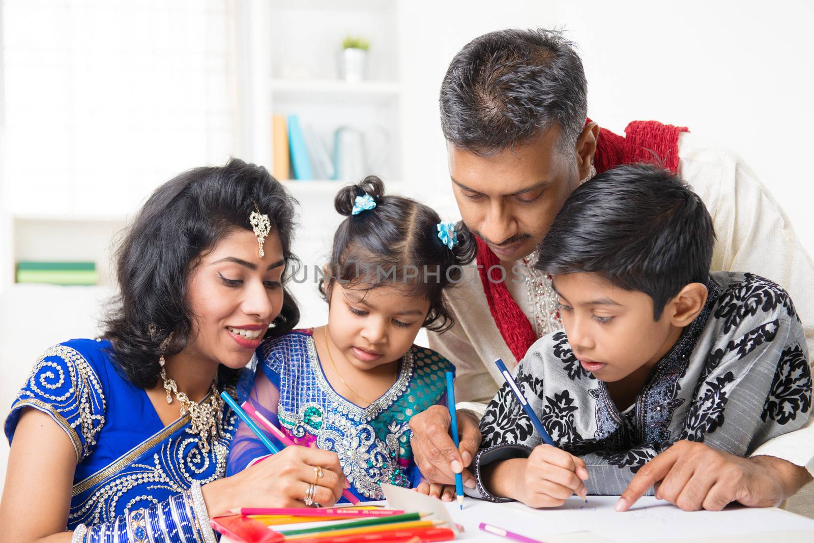 Asian Indian family drawing and painting picture at home. India family lifestyle. Happy parents and children having fun.