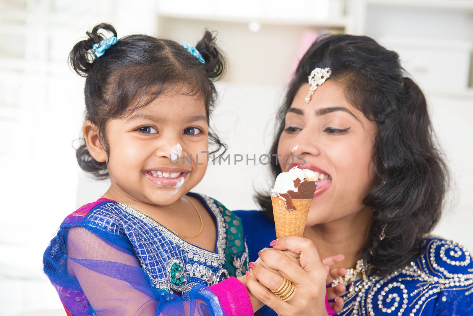 Eating ice-cream. Happy Asian India family sharing ice-cream at home. Beautiful Indian child feeding mother.