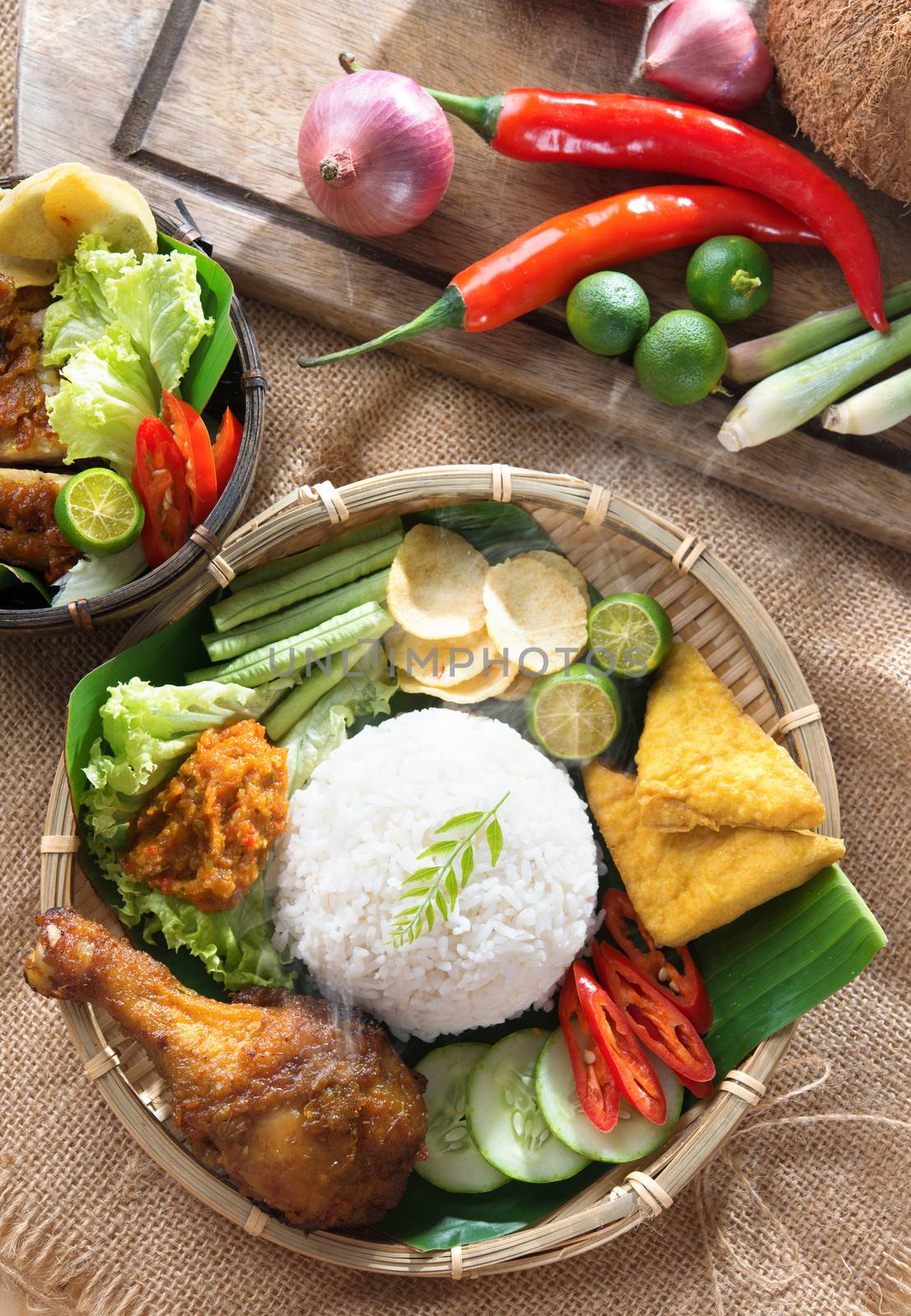 Popular Indonesian local food nasi ayam penyet, indonesian fried chicken rice with sambal belacan. Fresh hot with steam smoke.