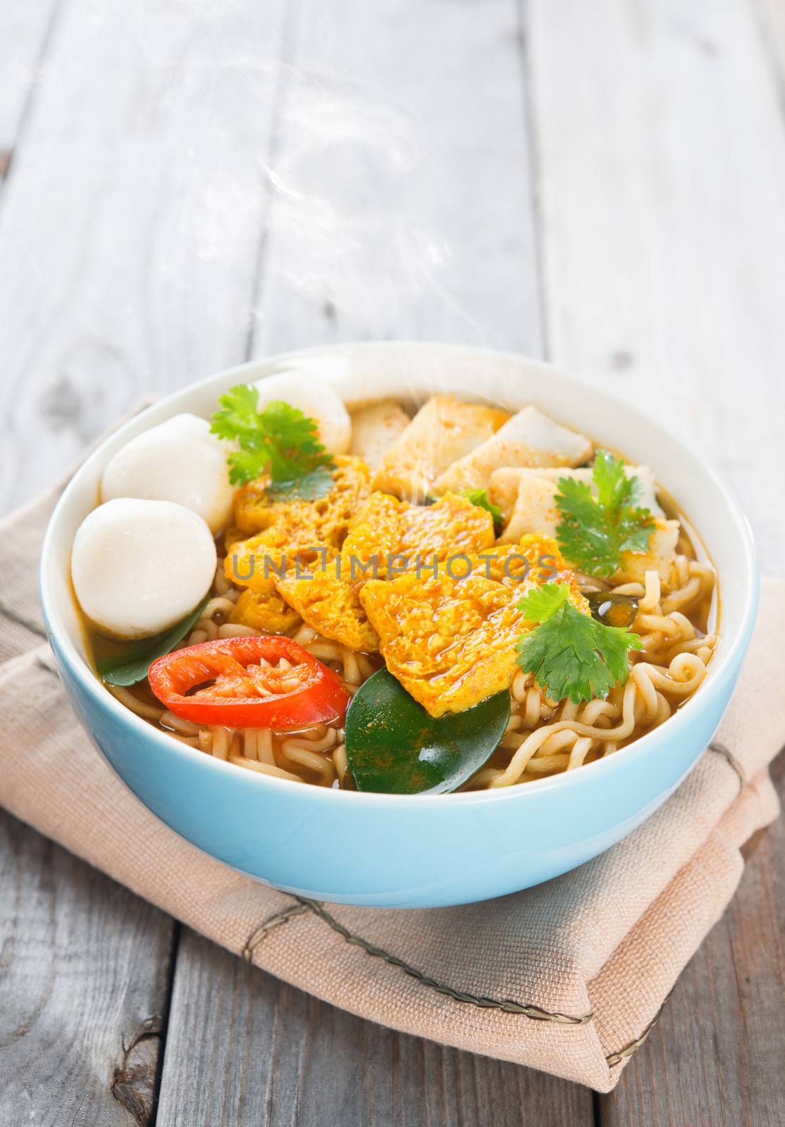 Spicy curry instant noodles. Asian cuisine, ready to serve on wooden dining table setting. Fresh hot with steamed smoke.
