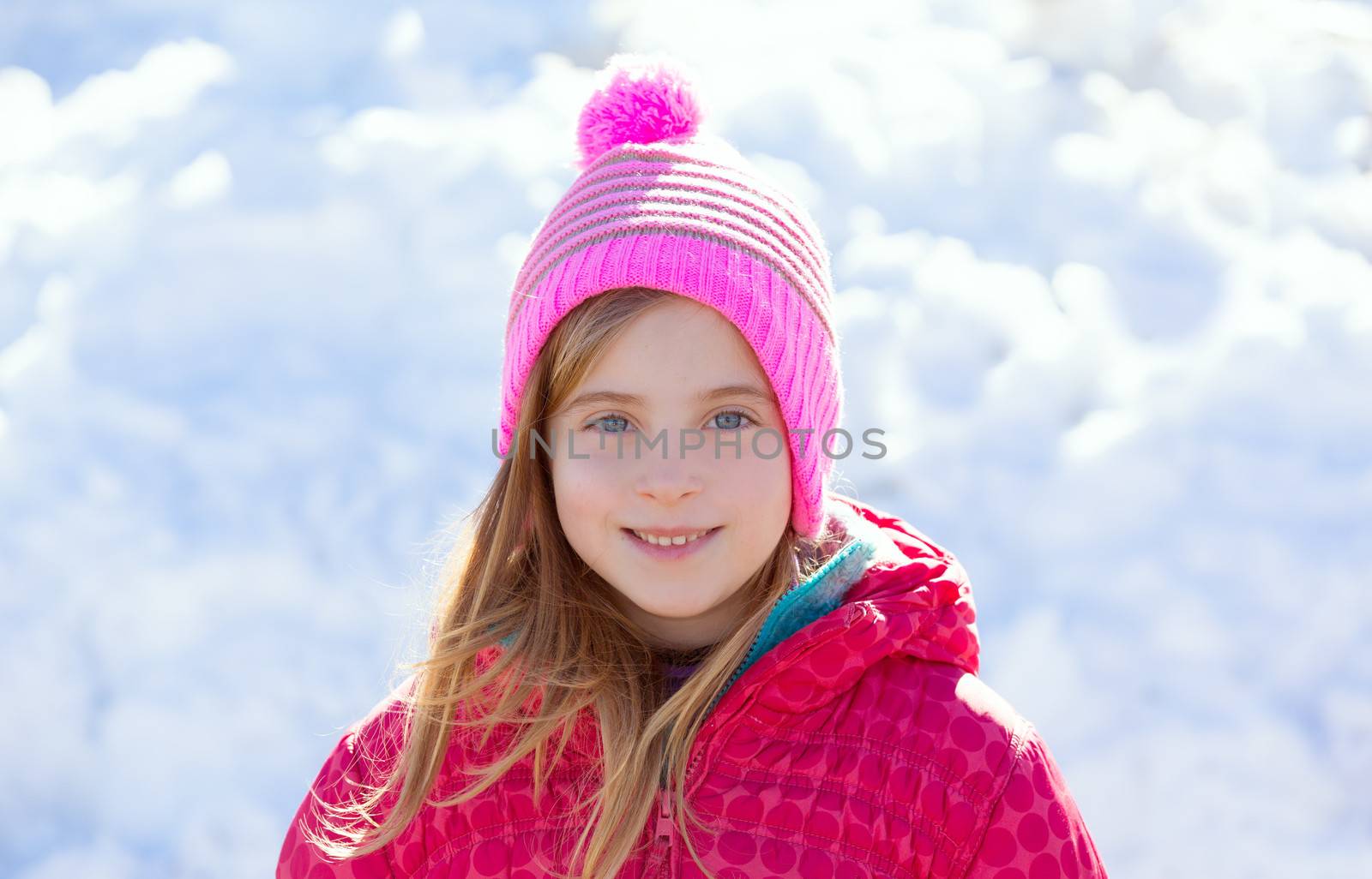 Blond kid girl winter pink hat in the snow smiling happy