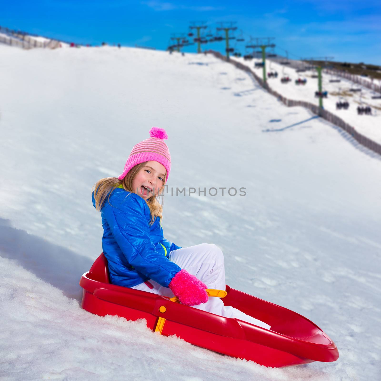 Kid girl playing sled in snow with winter wool pink hat
