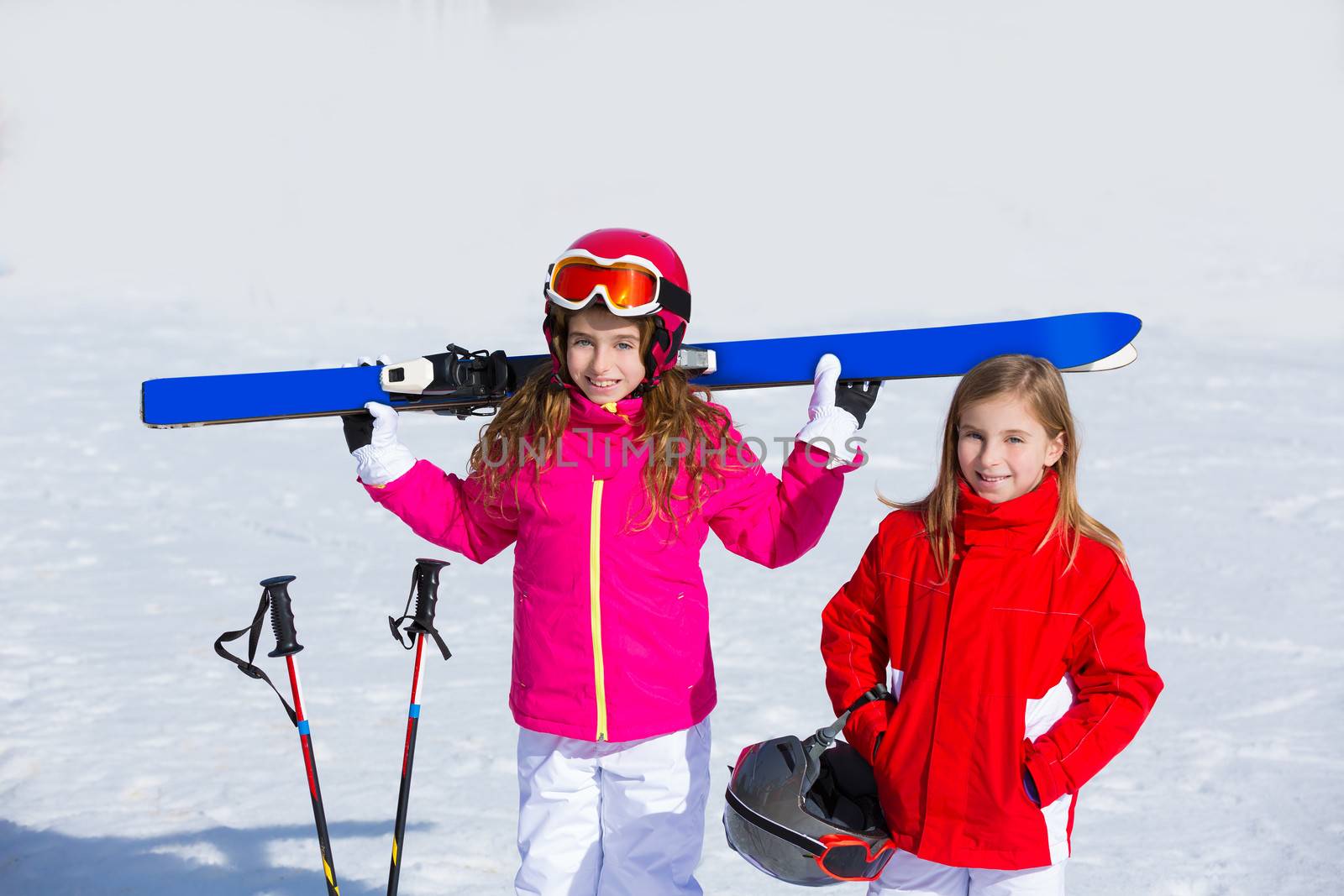 Kid girls sister in winter snow with ski equipment helmet goggles poles