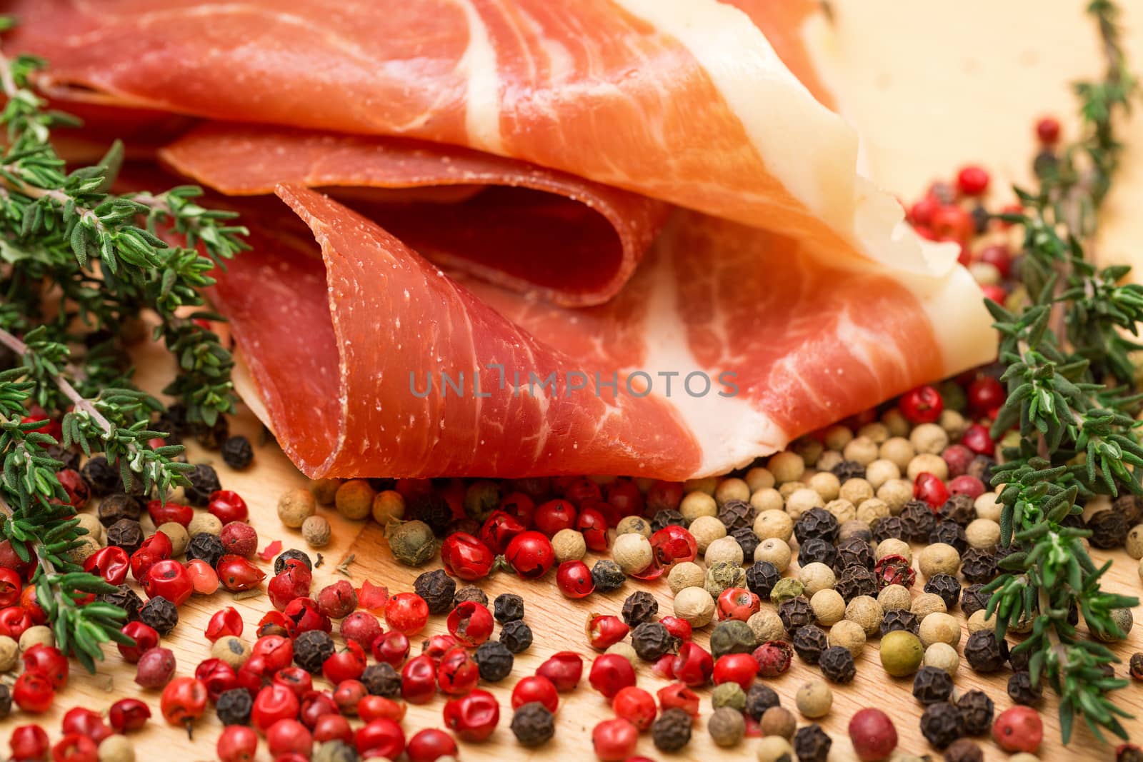 Dry thyme, multicolored peppercorn and hamon, closeup on wooden background