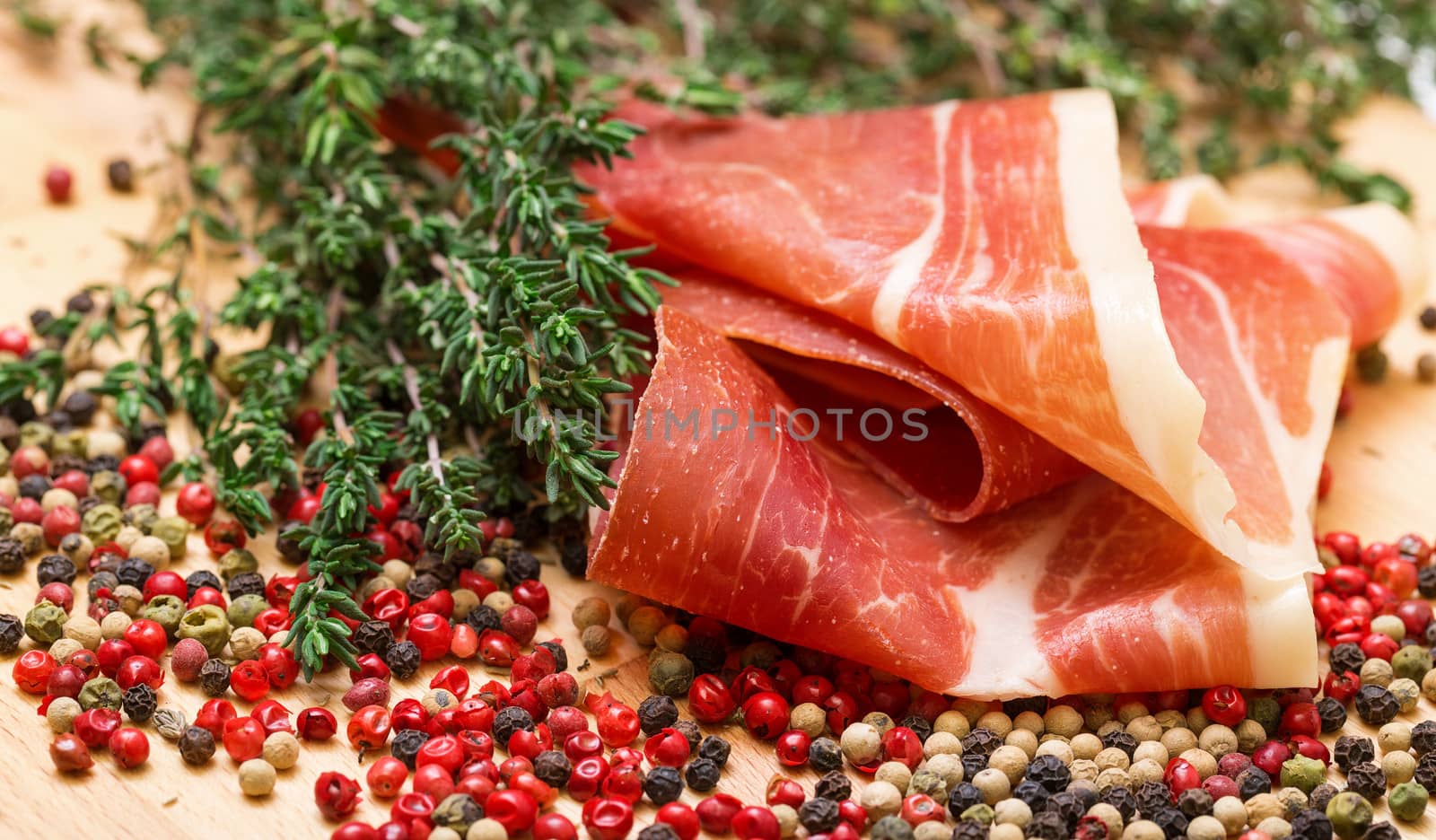 Dry thyme, multicolored peppercorn and hamon, closeup on wooden background