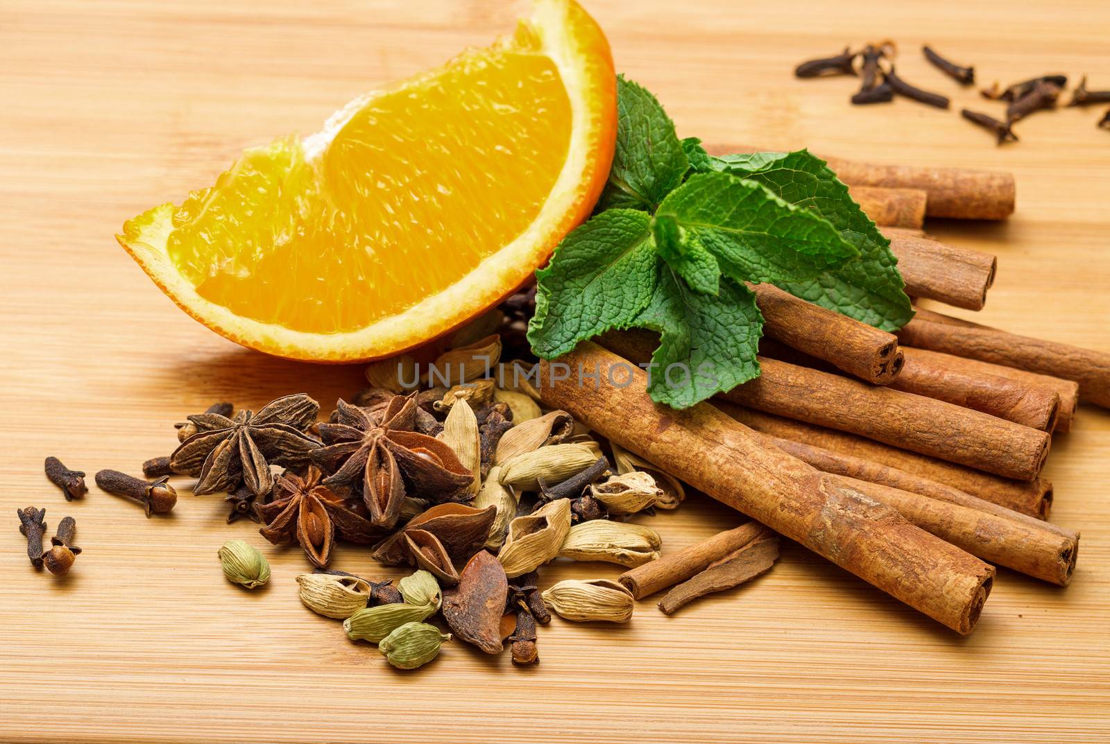 Multicolored spice with orange closeup on wooden background
