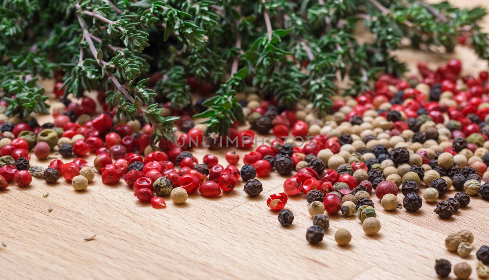 Dry thyme with multicolored peppercorn closeup on wooden background