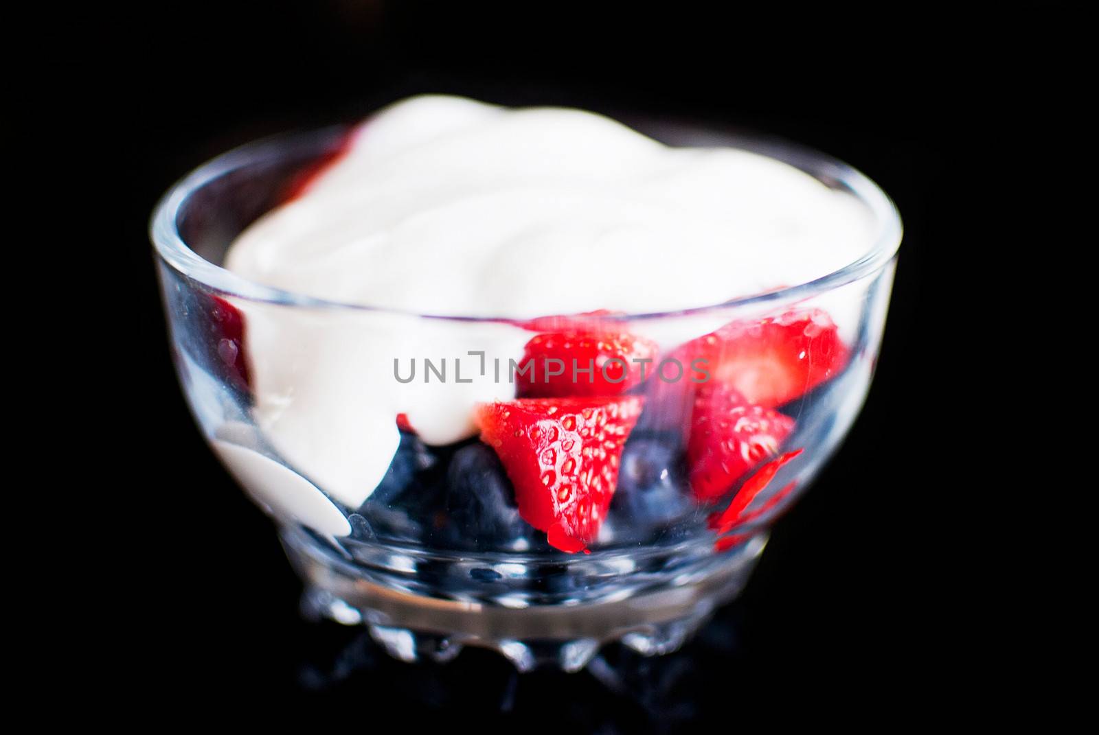strawberry and blueberry yoghurt in a bow isolated on black background