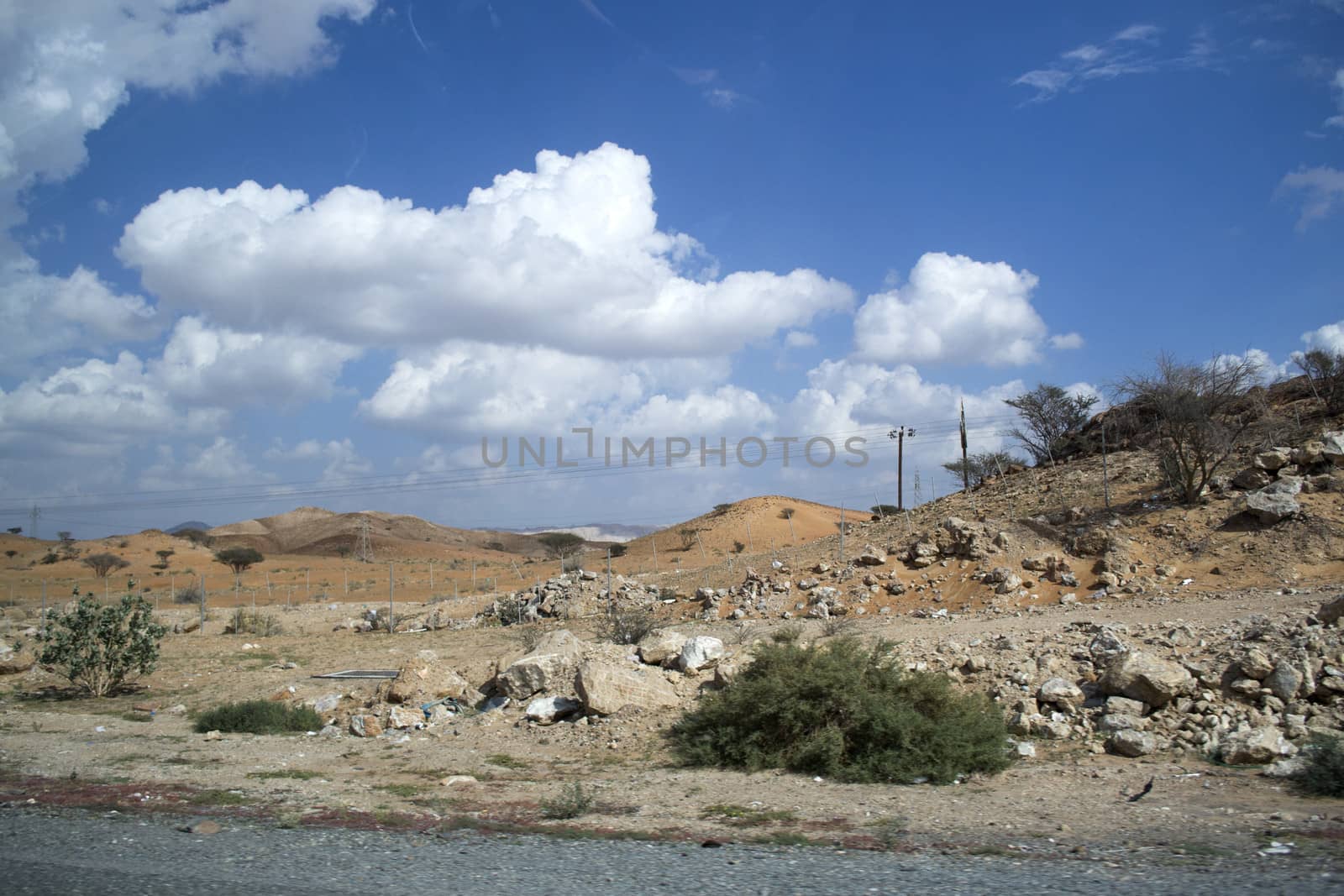 Desert landscape with blue sky, white clouds and golden sands