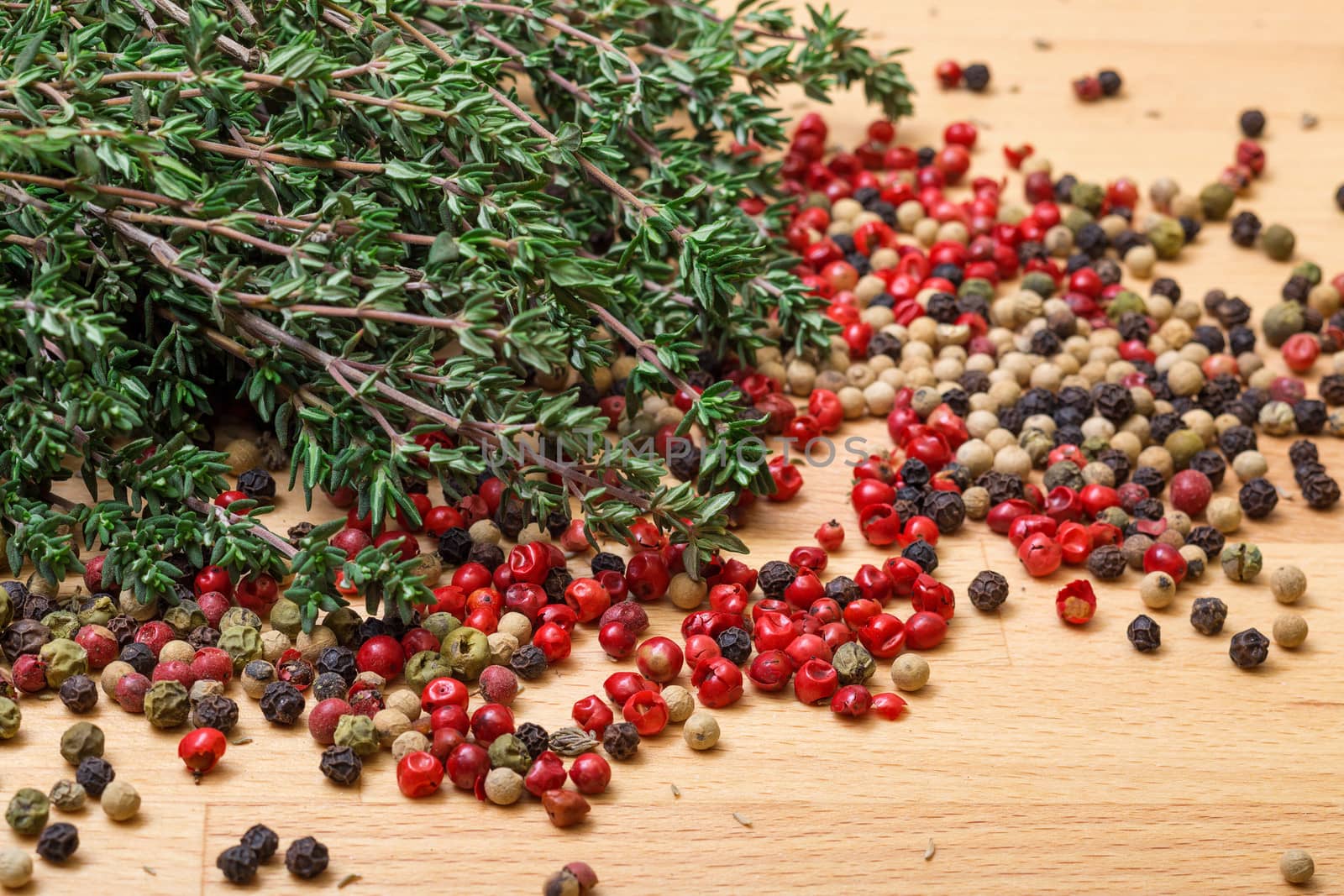 Dry thyme with multicolored peppercorn closeup on wooden background