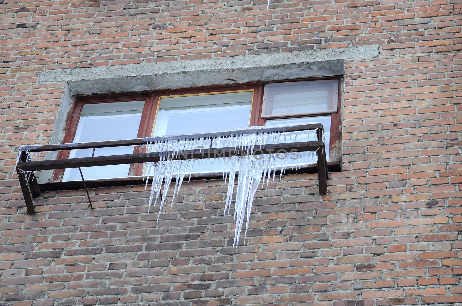 Big icicles at a window, against a brick wall