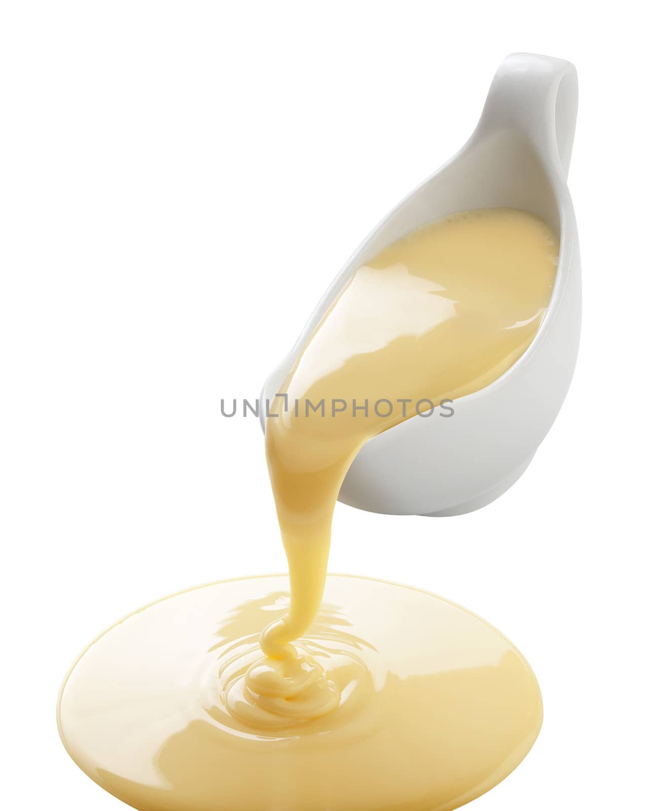 Isolated yellow condensed milk flowing from white sauce-boat