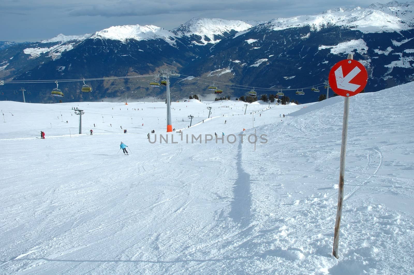 Slope direction sign and skiers on slope in Austria nearby Kaltenbach in Zillertal valley