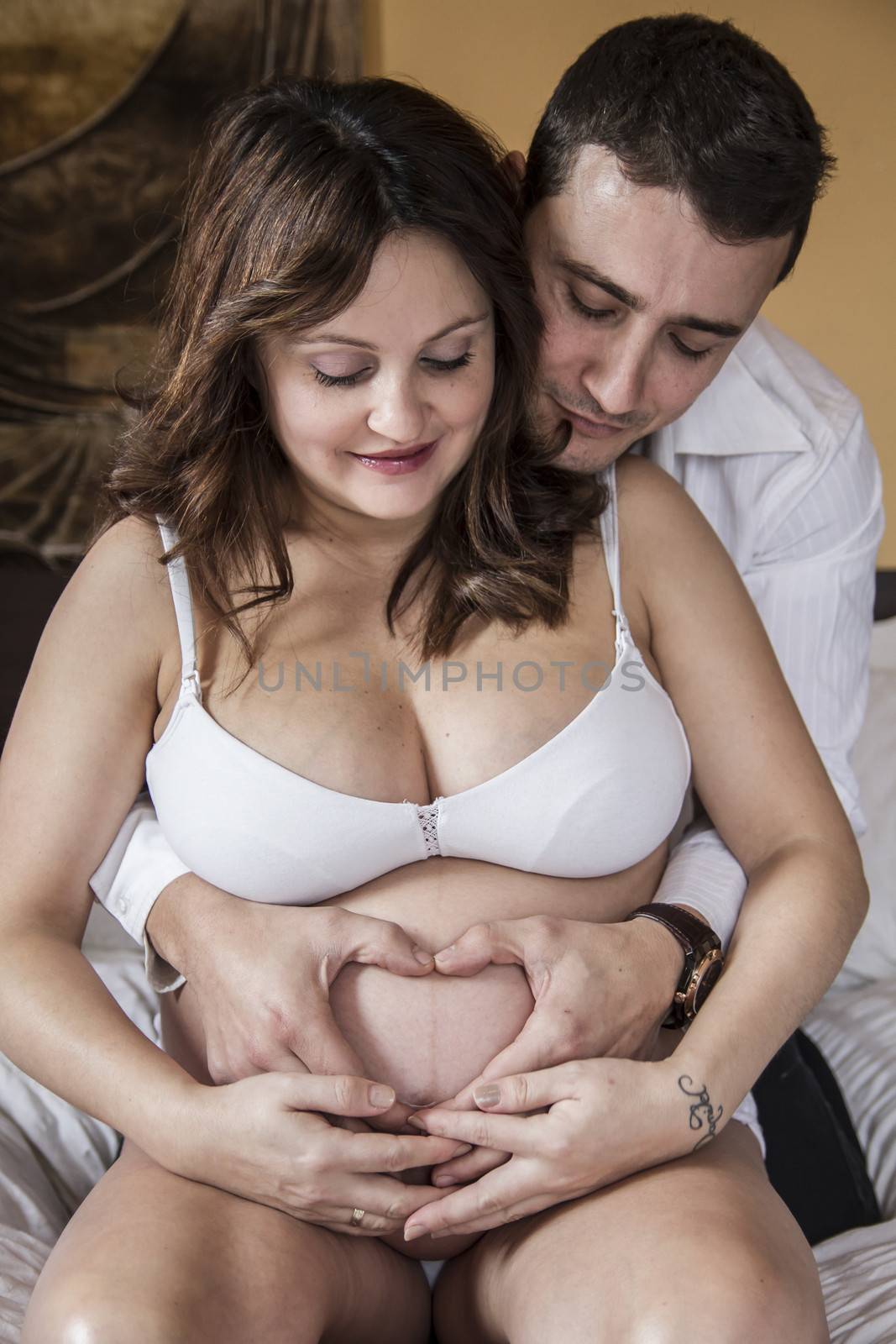 Couple, Family With Pregnant Mother Relaxing On bed Together