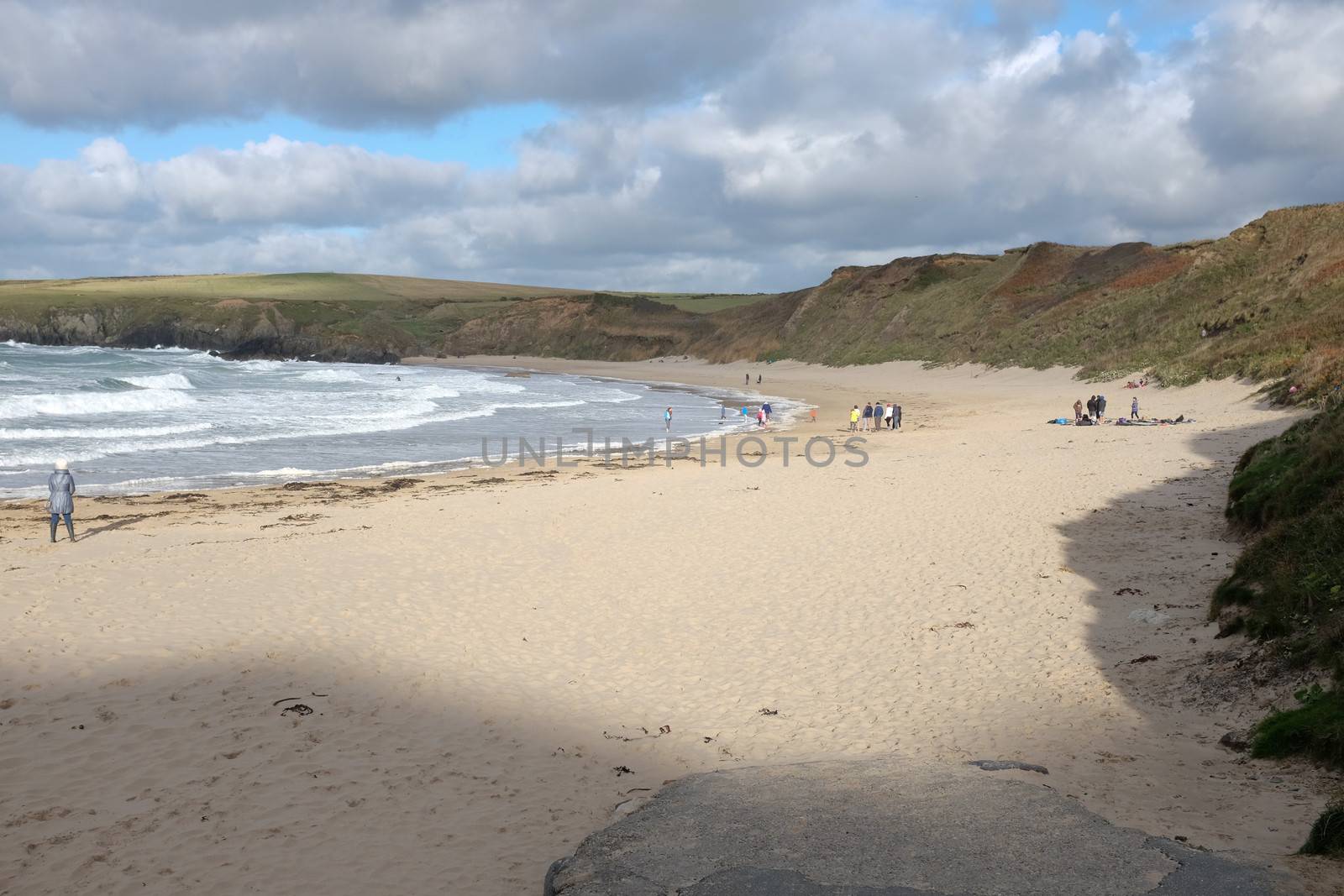 White sandy beach with people near the sea with waves, Whistling Sands, Porth Oer, on the Lleyn peninsular, North Wales, UK.