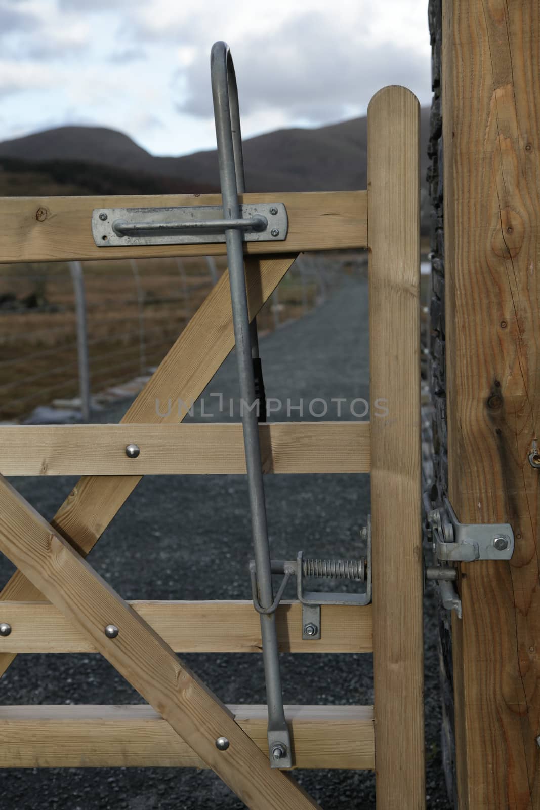 A wooden gate and post with a dual directional metal pull handle latch.