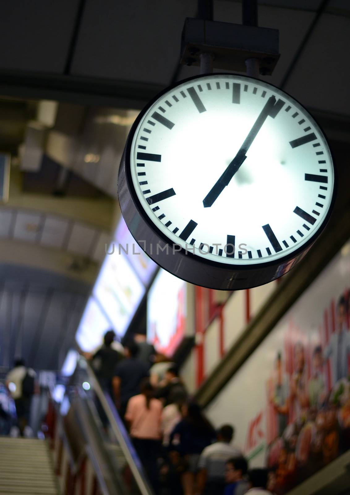 Public clock in railway station, people background 