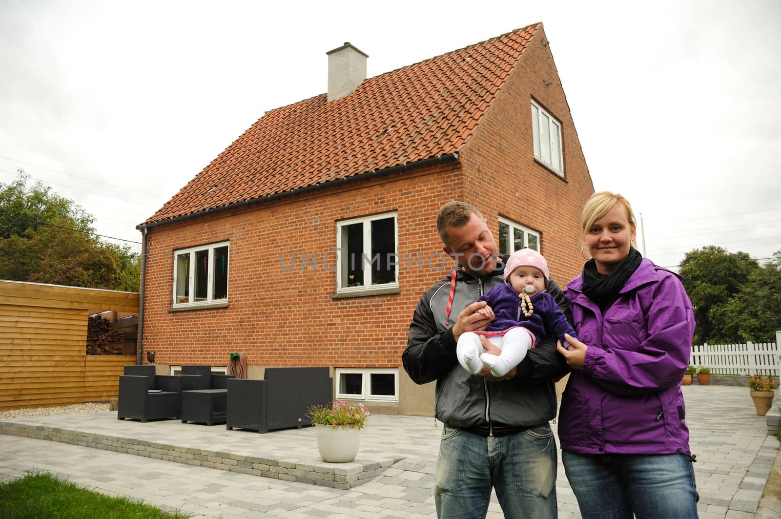 Happy family in front of house by cfoto