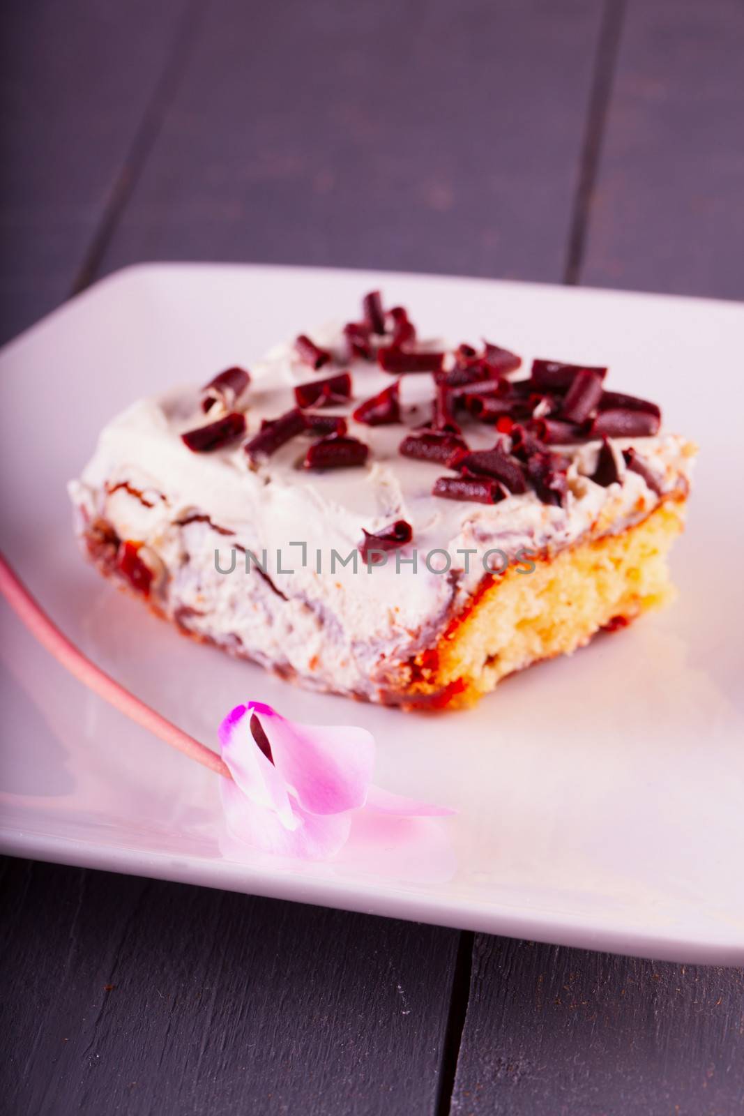 Cake slice with cyclamen over white plate, focus on flower