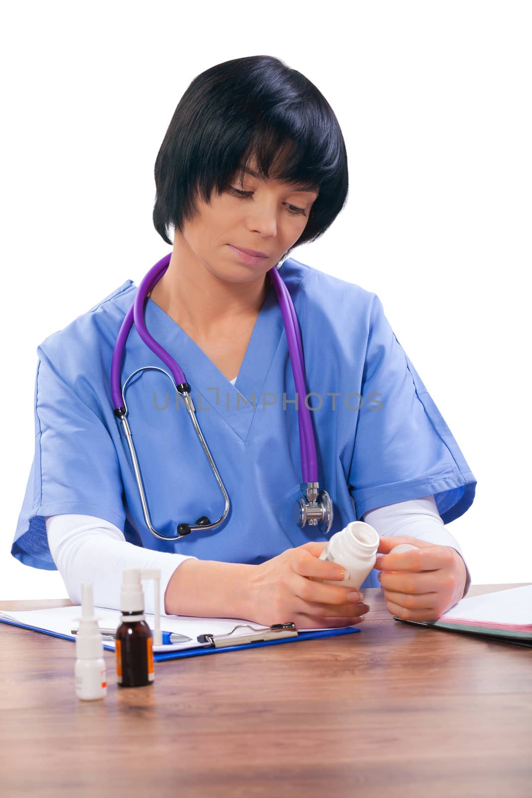asian female doctor sitting at table and holding bottle of pils by mihalec